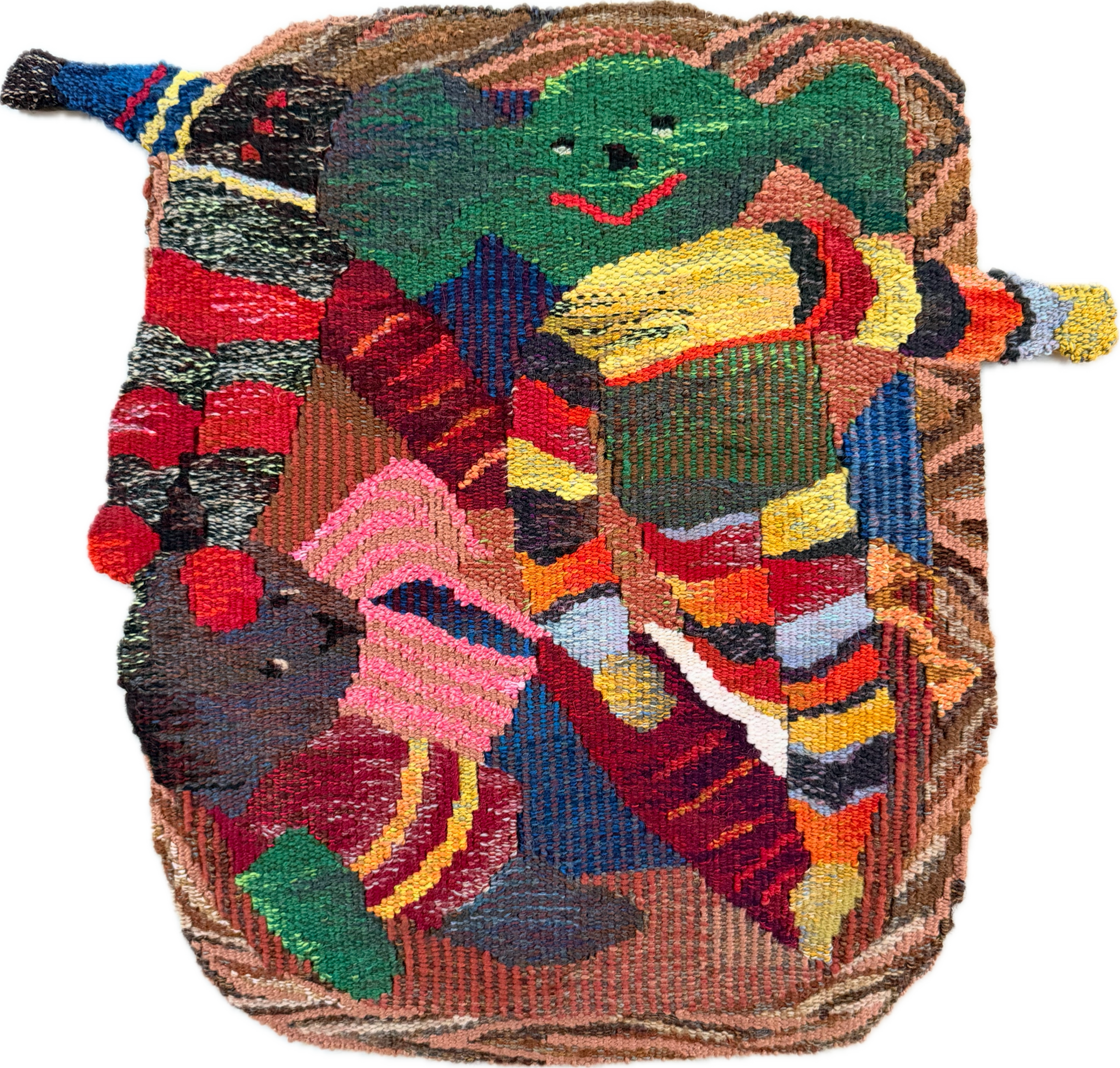 A colorful hand-stitched tapestry featuring a smiling cartoon dog with green fur, black eyes, and a red tongue, set against a multicolored background of various abstract shapes.