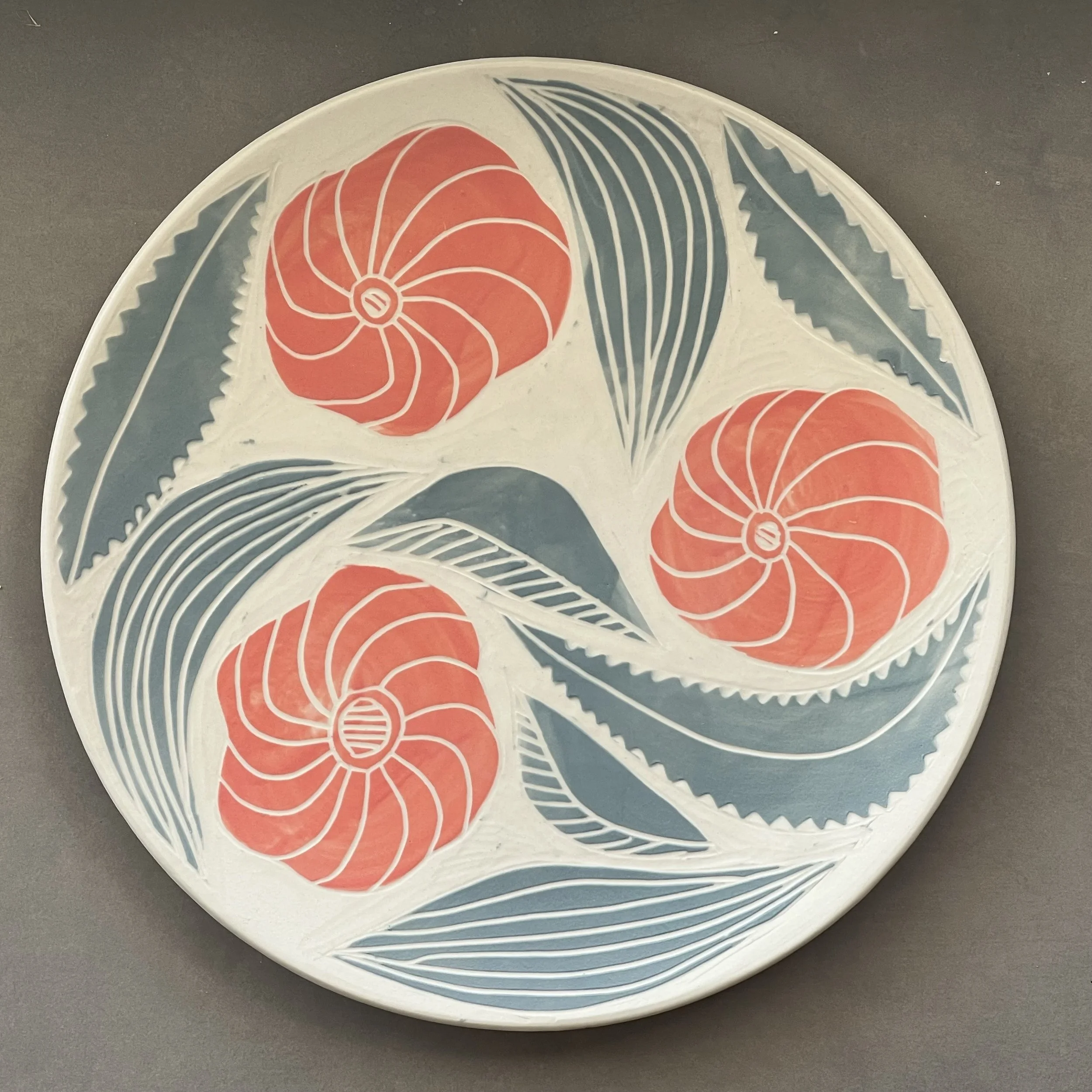 Dimity Kidston sgraffito hand carved ceramic plate with a floral and wave pattern in red, blue, and white.