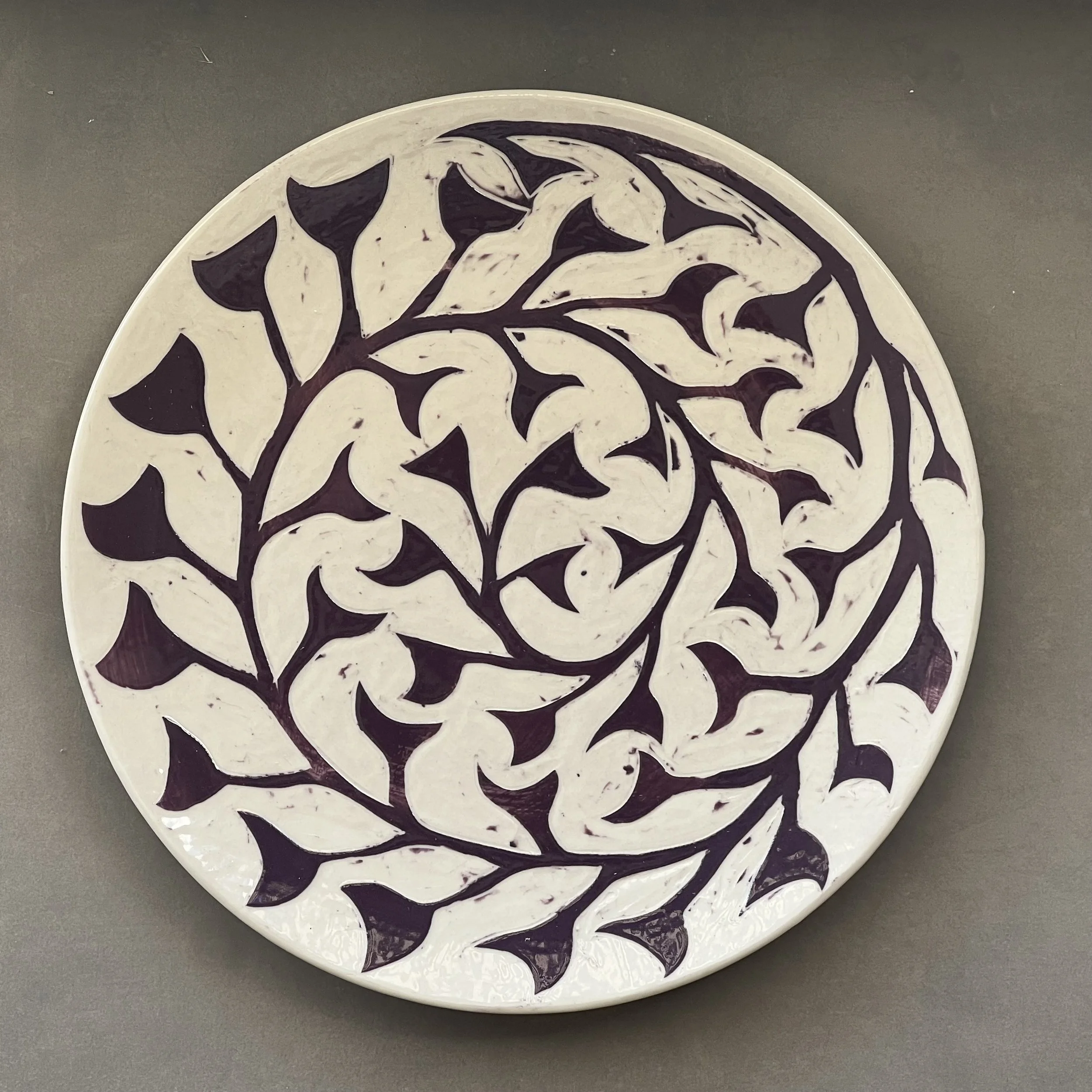 Dimity Kidston sgraffito hand carved ceramic plate with a black and white abstract leaf or plant pattern.