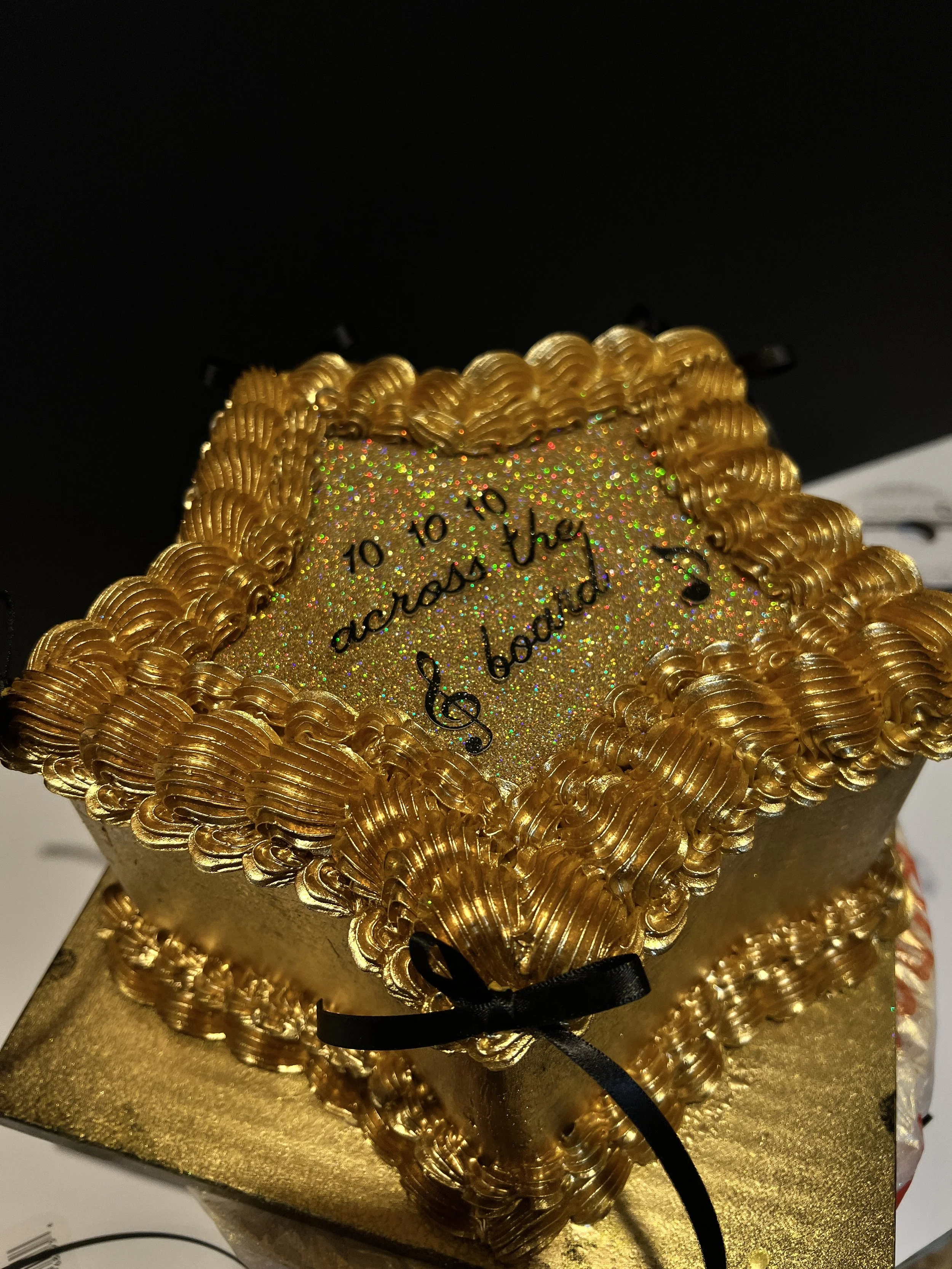 Close-up of a gold star-shaped cake with intricate swirls and glitter. 