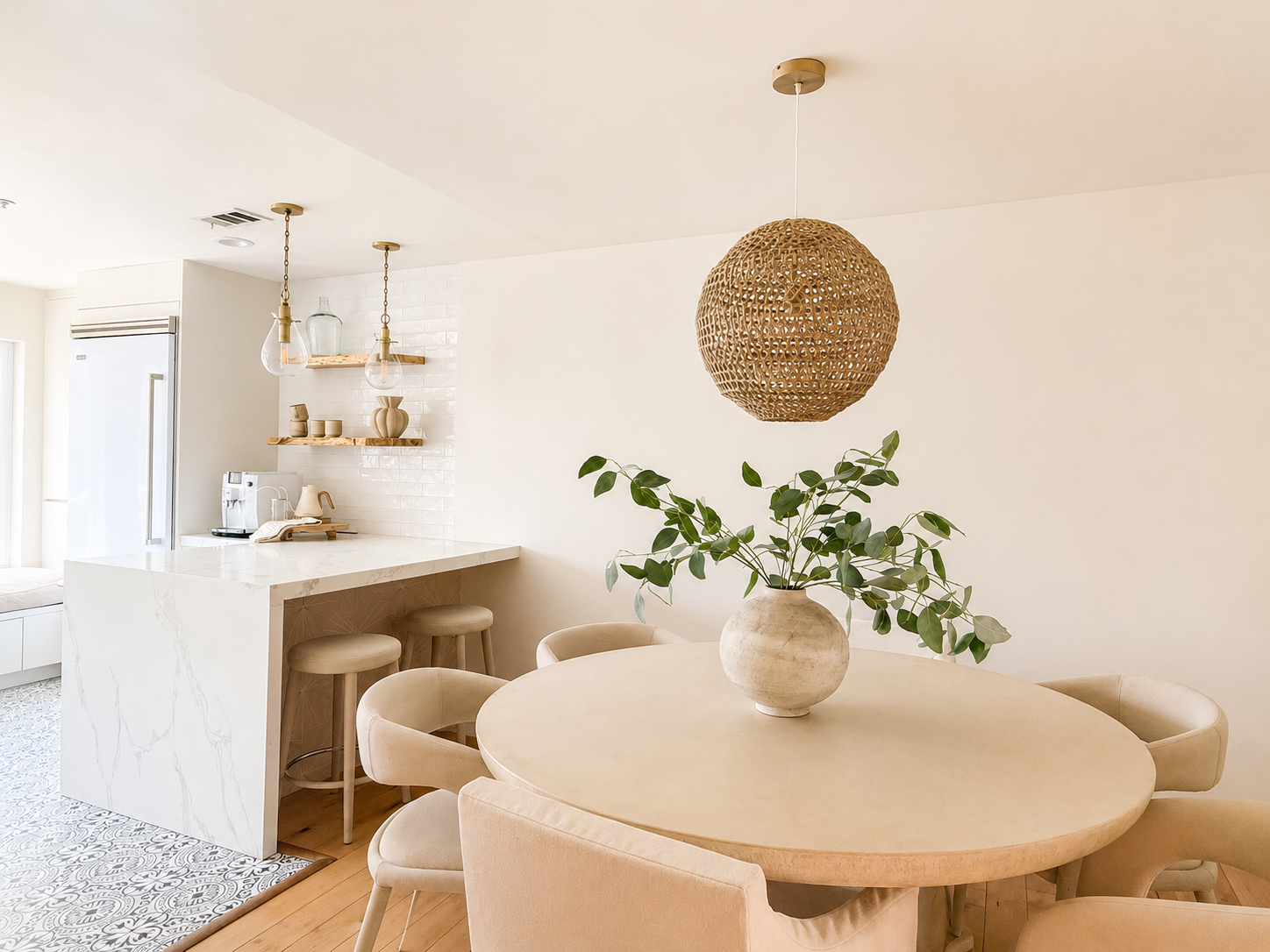 Light-filled dining room at The Solana House with a round table, woven pendant, natural wood accents and adjoining coastal kitchen.