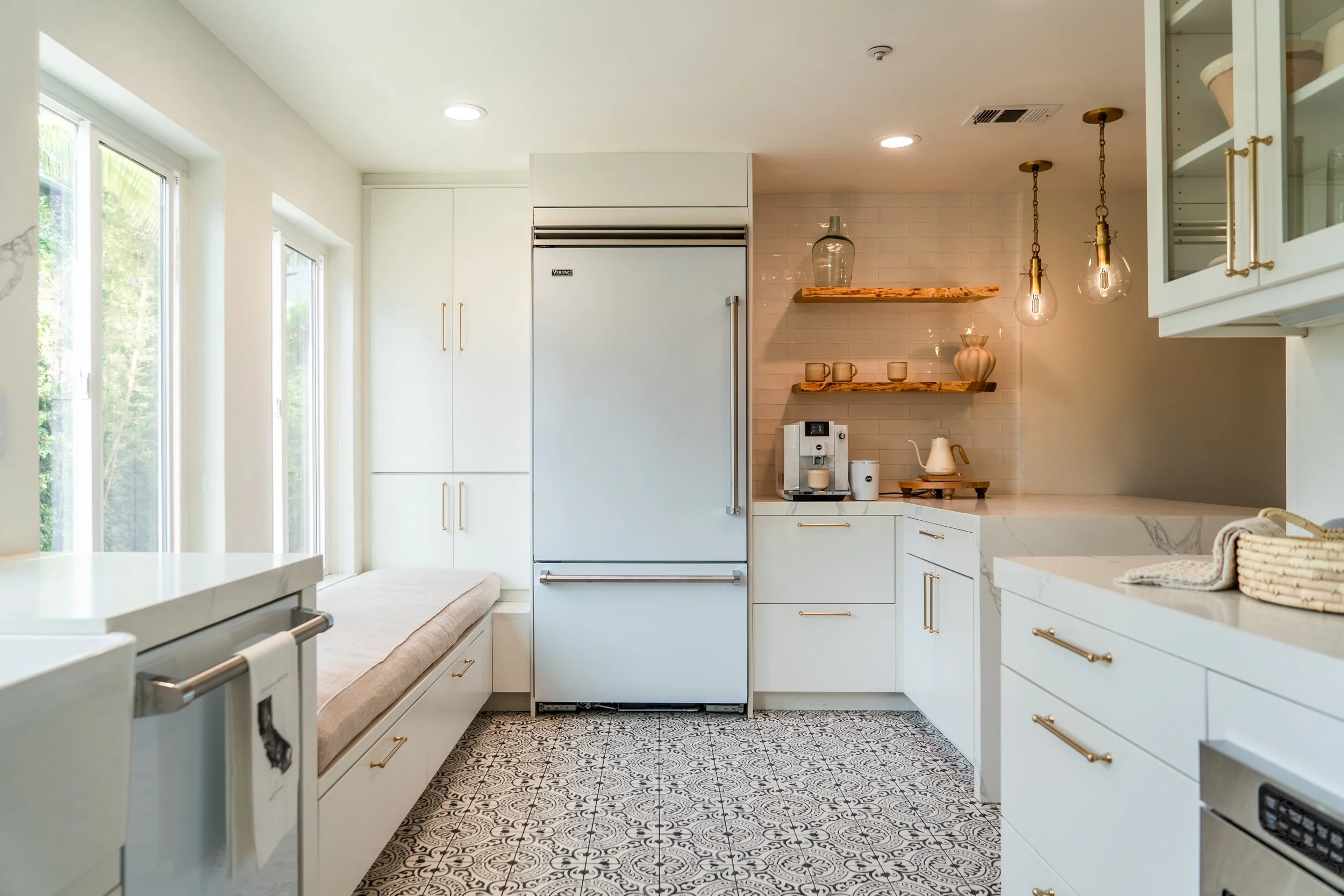 Bright coastal kitchen at The Solana House with white cabinetry, built-in refrigerator, coffee station and warm wood shelving.
