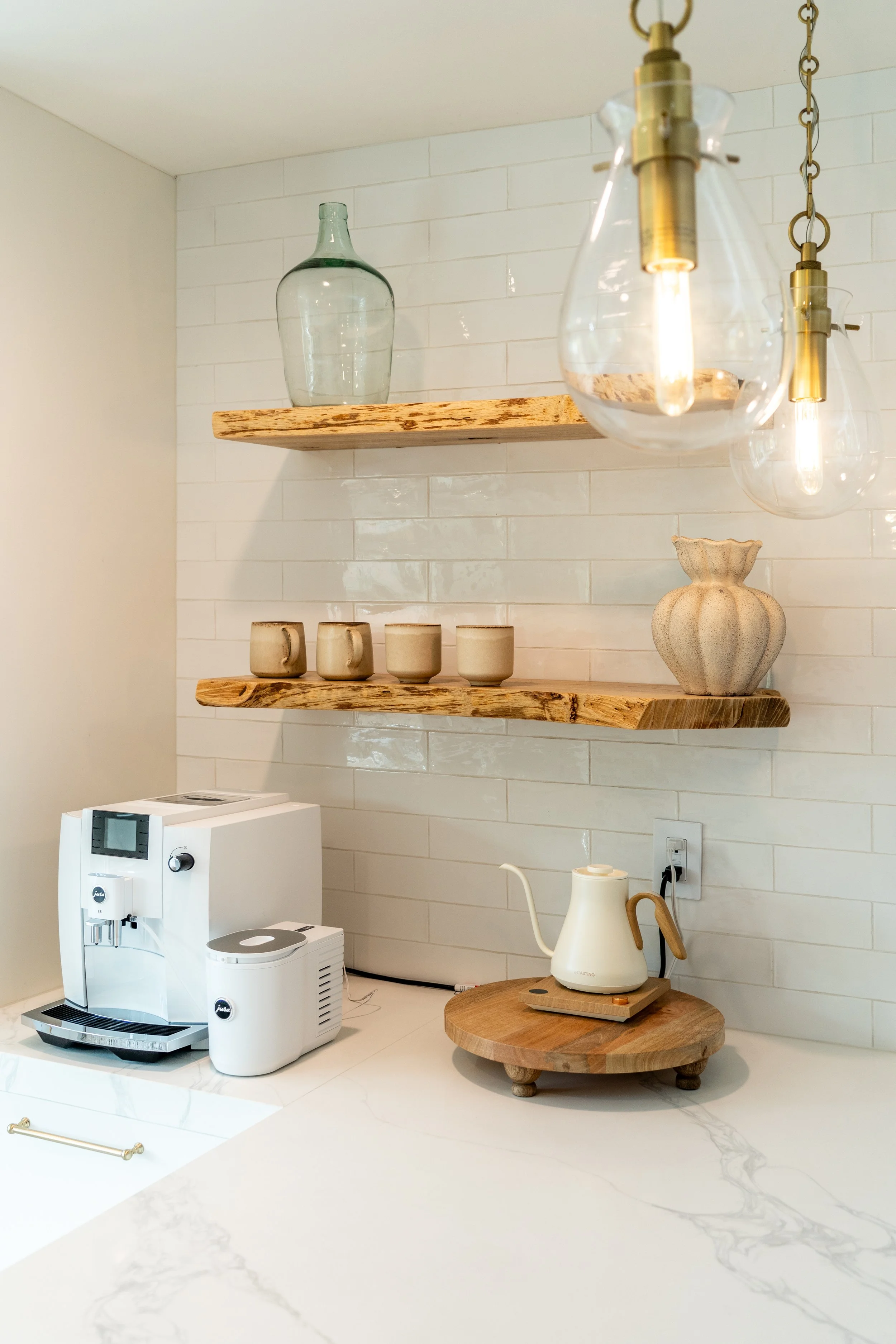 Warm wood open shelving and brass pendant lights add coastal character to The Solana House kitchen.