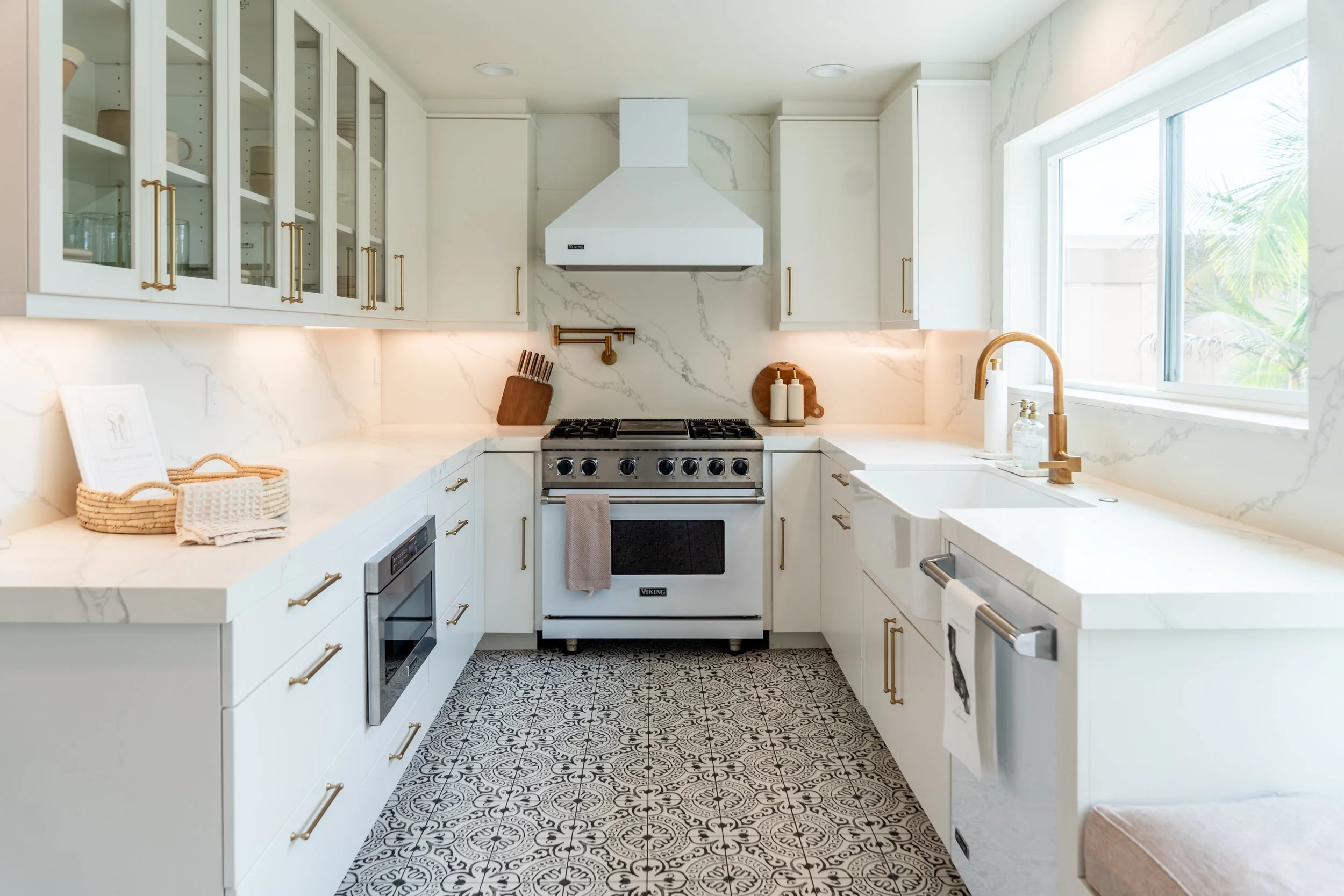 Bright fully equipped kitchen at The Solana House with white cabinetry, Viking range, patterned tile floor, and natural light.