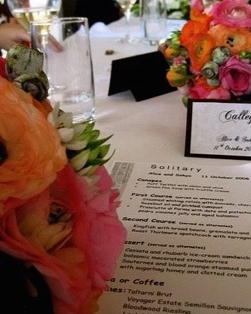 A table at a fancy event with floral centerpieces, a menu, and name cards.