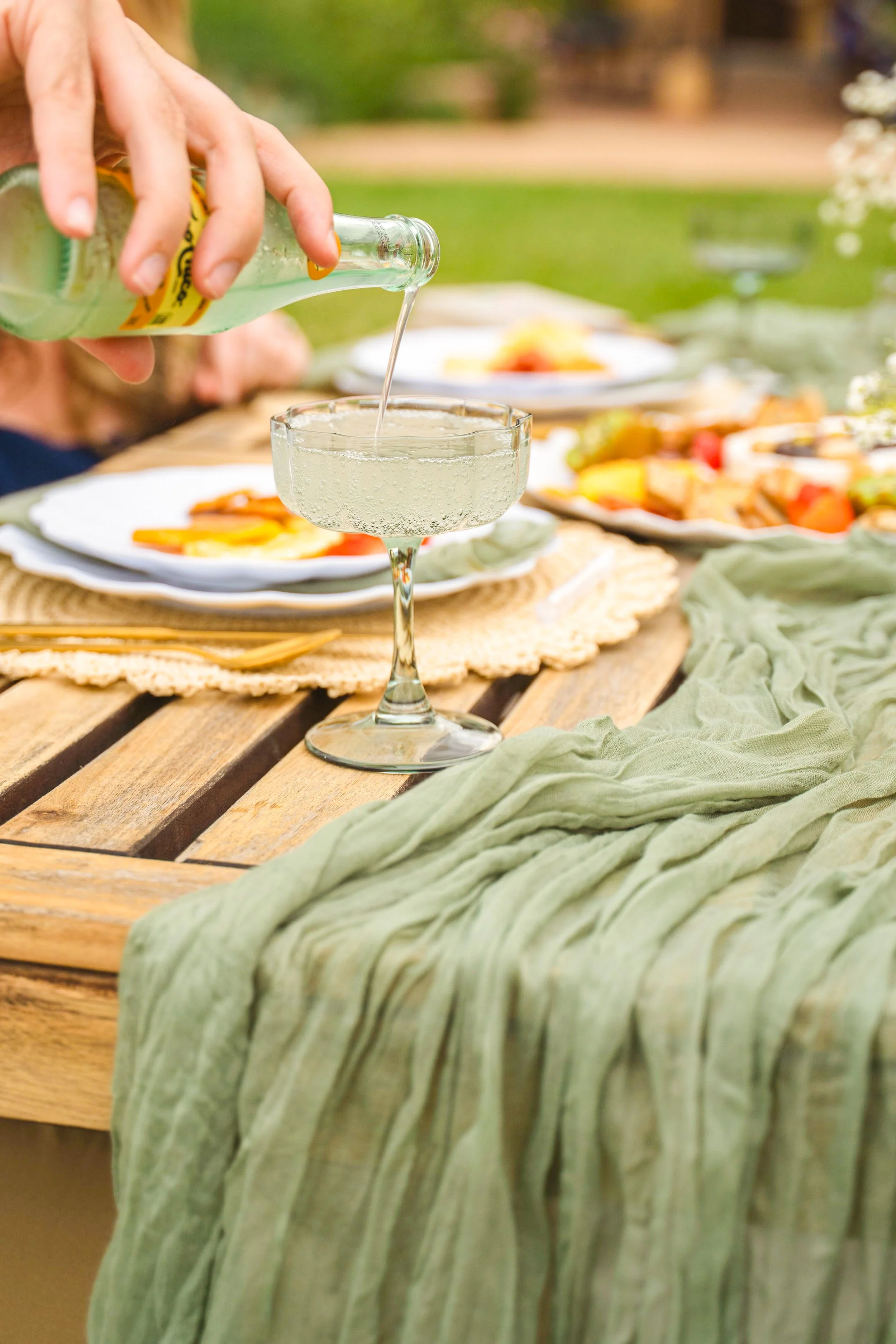 Man pouring sparkling water at luxury picnic