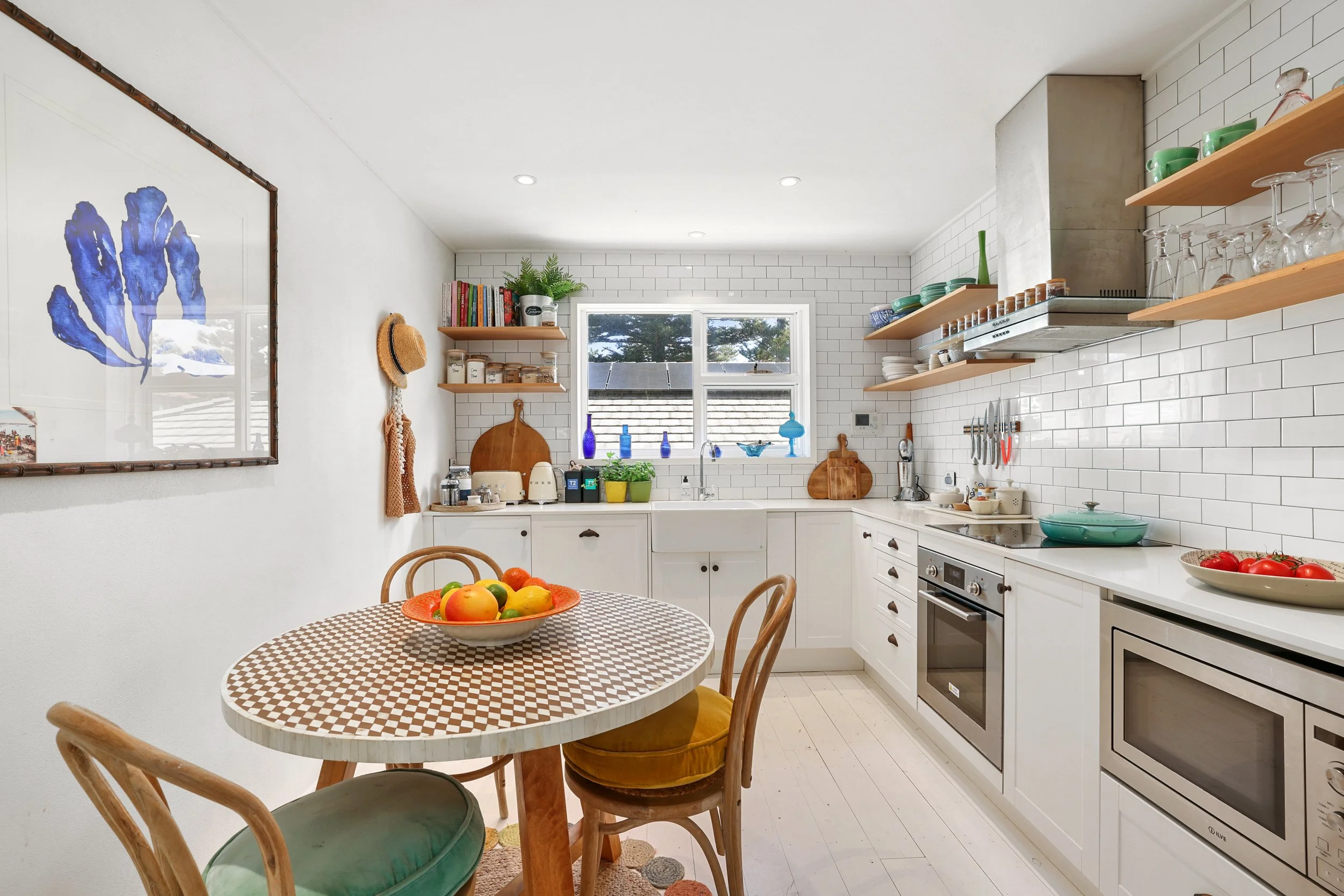 Bright open kitchen and dining area at Sea Fan, with white cabinetry, colourful tableware and everything needed for meals, coffee and cocktails.