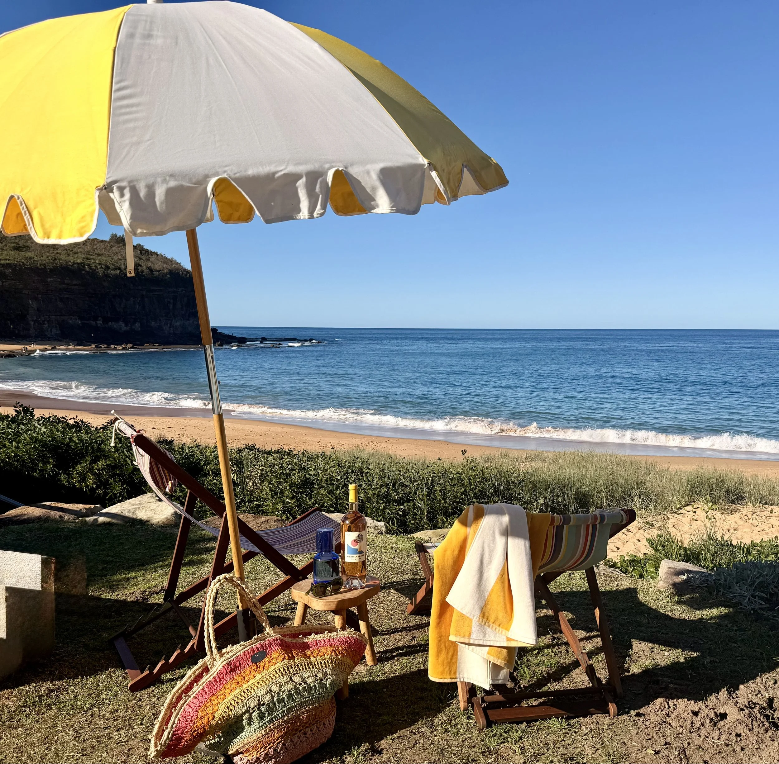 Sea Fan’s oceanfront lawn at the Basin, set up with a beach umbrella, deck chairs, beach towels and wine, with steps directly onto the beach.