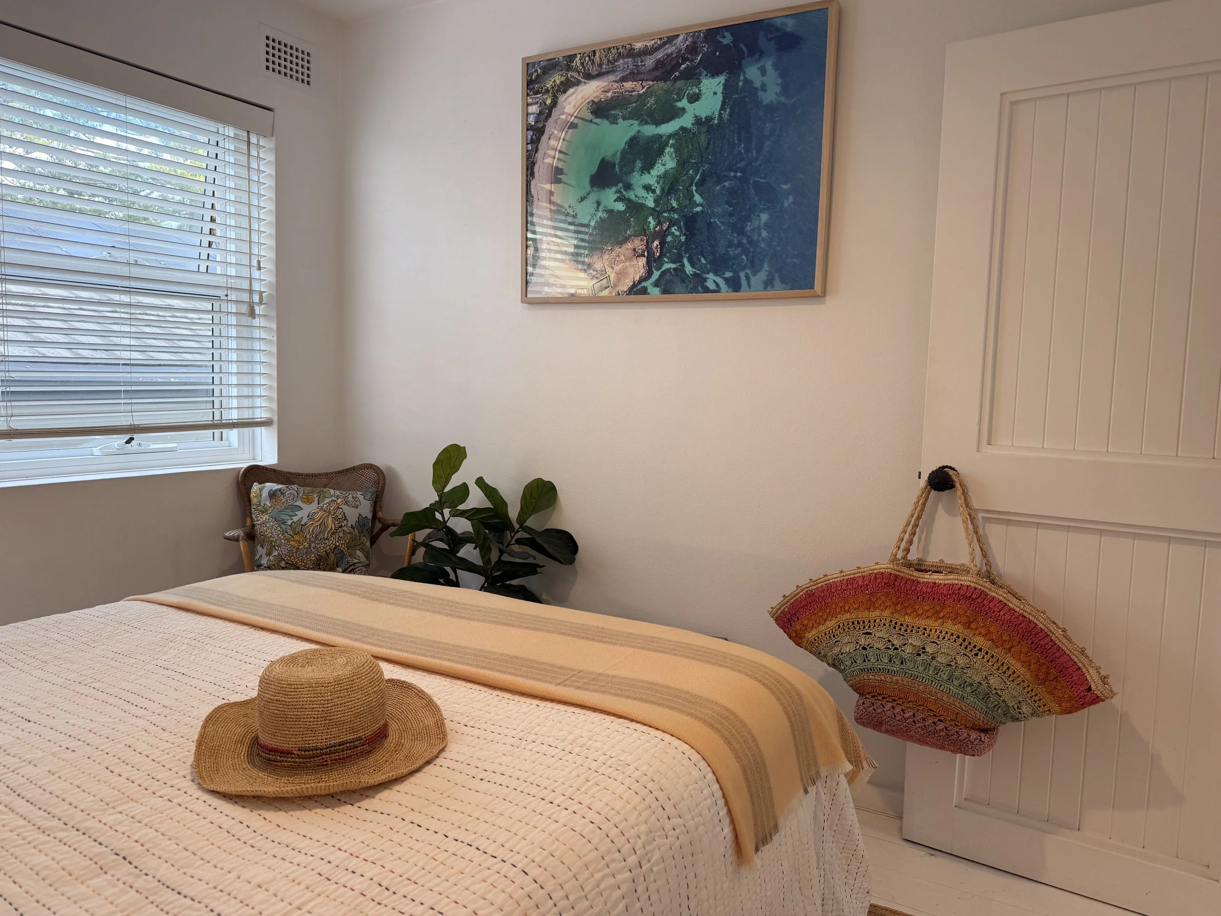 The Basin Room at Sea Fan, with a queen bed, white CULTIVER linen, The Basin coastal artwork and a colourful Sea Fan  beach bag.