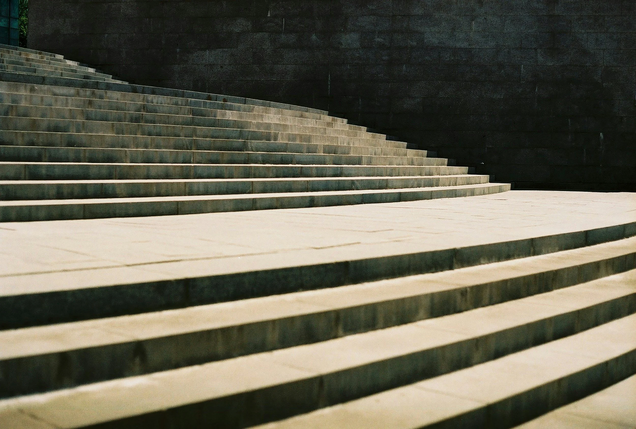 Concrete steps leading up to a dark textured wall in an urban setting.