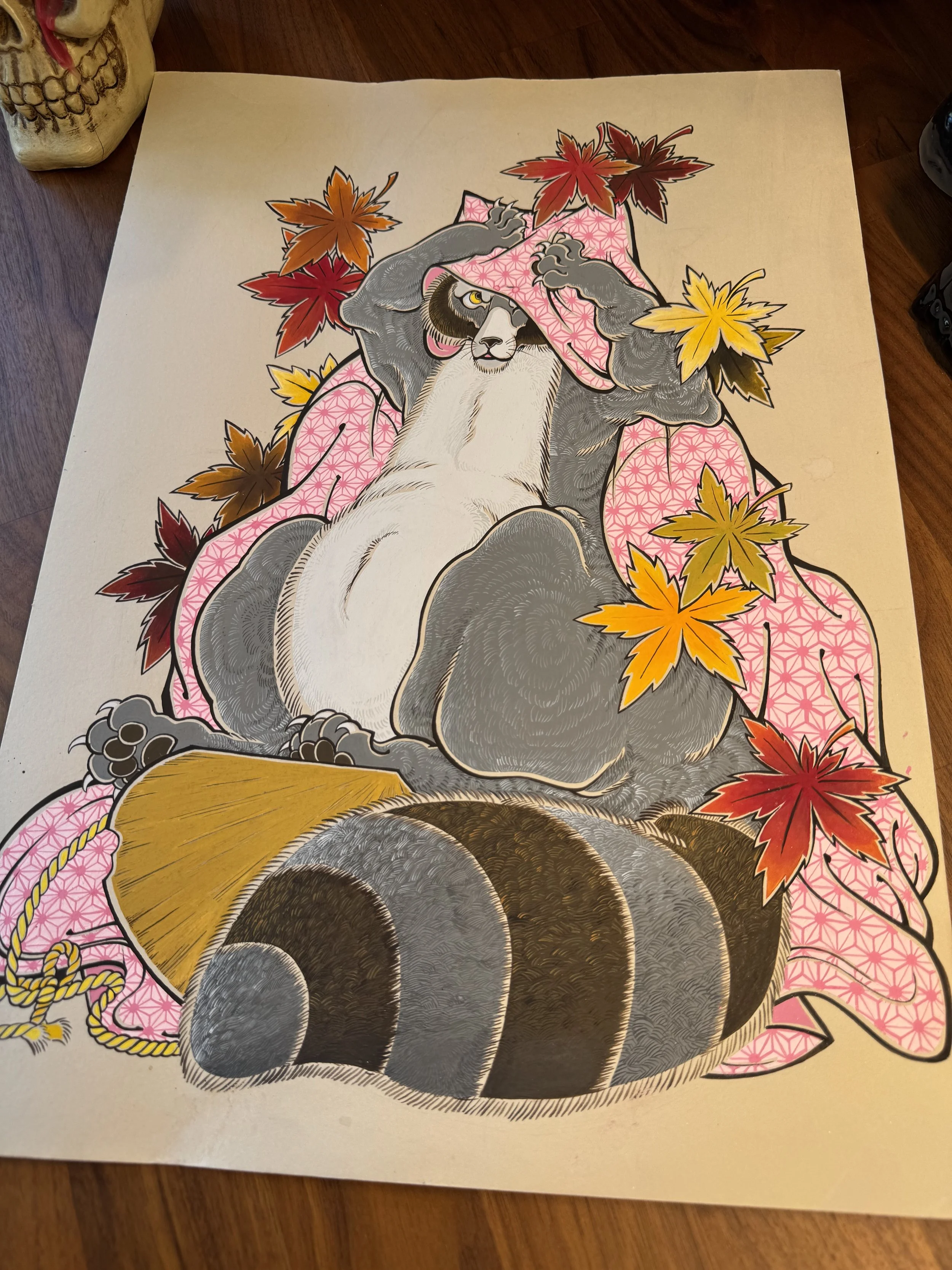 A colorful illustration of a roccon dog wearing a pink kimono with a geometric pattern, sitting beneath red, yellow, and orange maple leaves, with a background of beige paper.