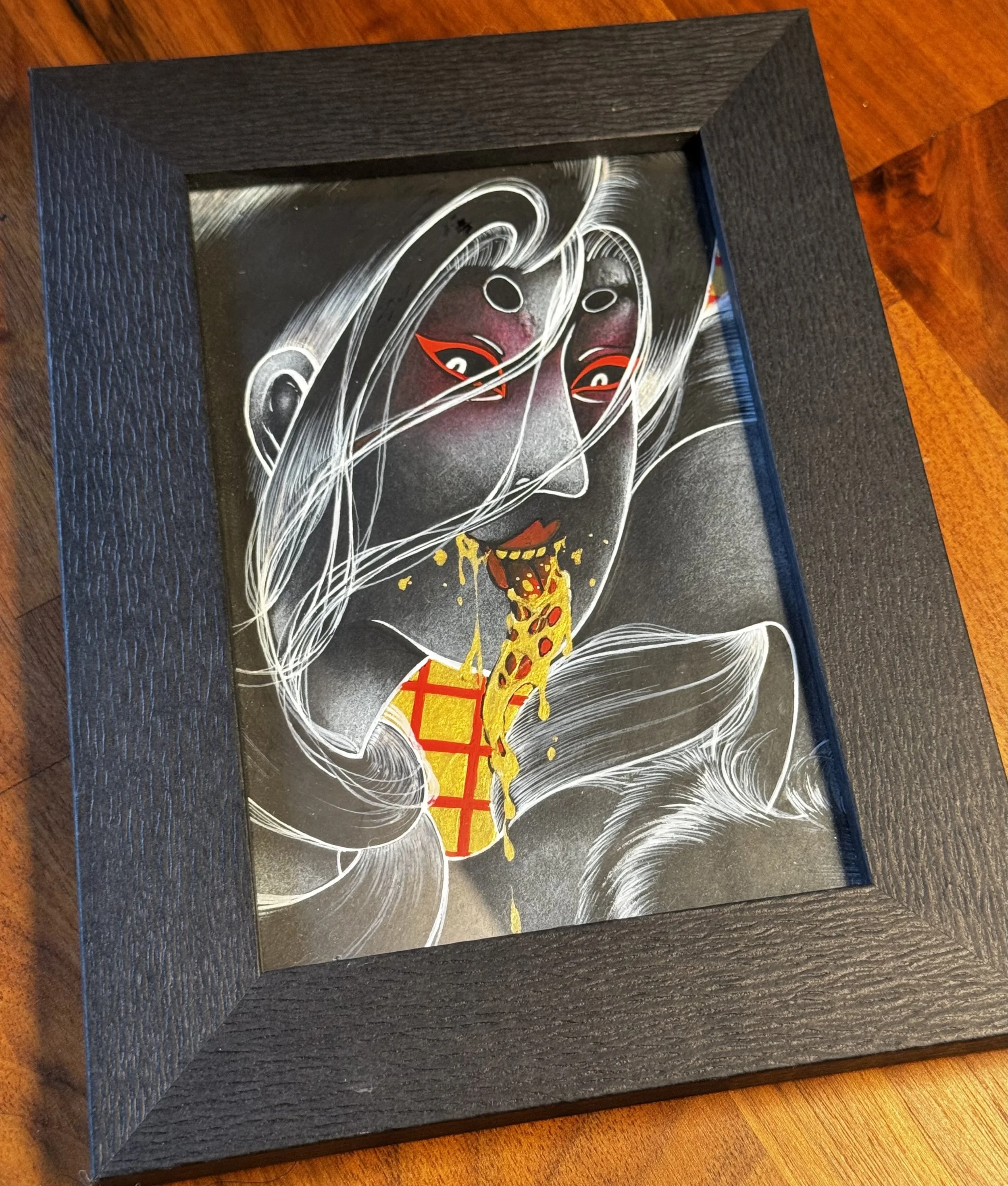 A framed artwork of a Rokurokubi, with tongue sticking out covered in golden oil, against a black background.