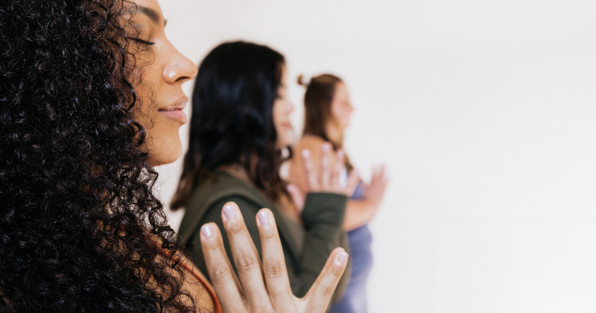women meditating with eyes closed and hands in prayer – representing emotional strength, reflection, and the Healing Virtue of The Soul Award