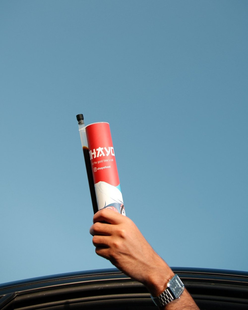 Hand raising an Ohayo against a blue sky