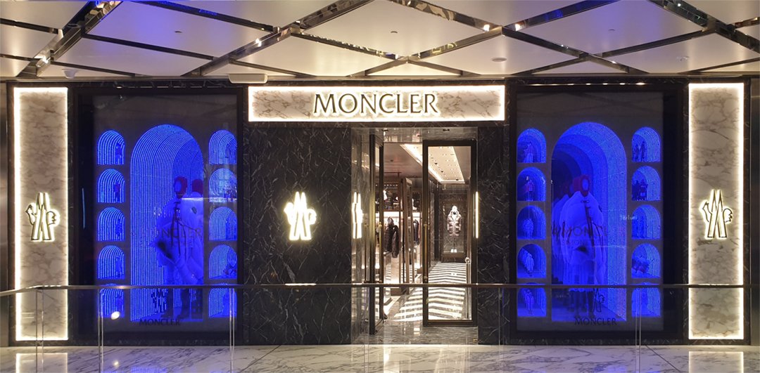Custom high end luxury retail brands window dressing, installation.Storefront sydney, with black marble walls, illuminated signs, and large digital windows displaying fashion images with blue lighting. HR Productions Sydney
