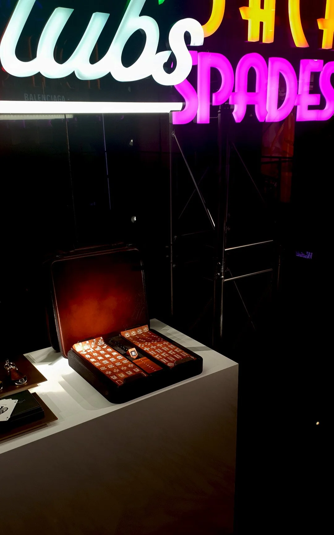 Neon sign with the words 'club' and 'spades', and a table with a red leather chair, a black box of dominoes, and a few other items. Custom high end luxury retail brands window dressing, installation, props, HR Productions Sydney