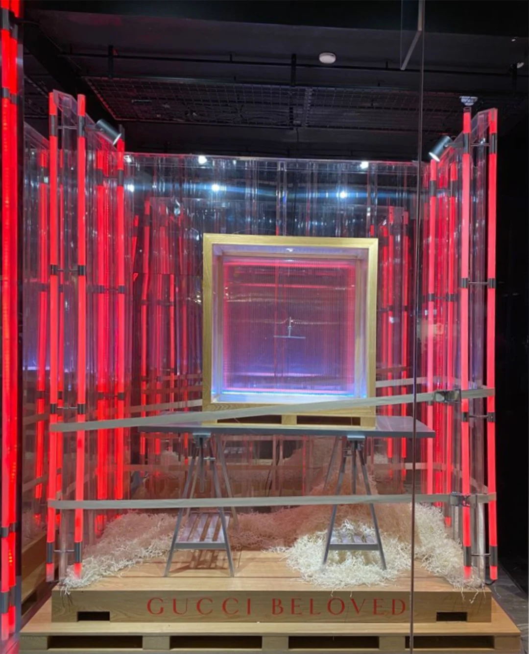 Custom high end luxury retail brands window dressing, installation.An art installation with red neon lights, a reflective backdrop, featuring a framed display in the centre. HR Productions Sydney