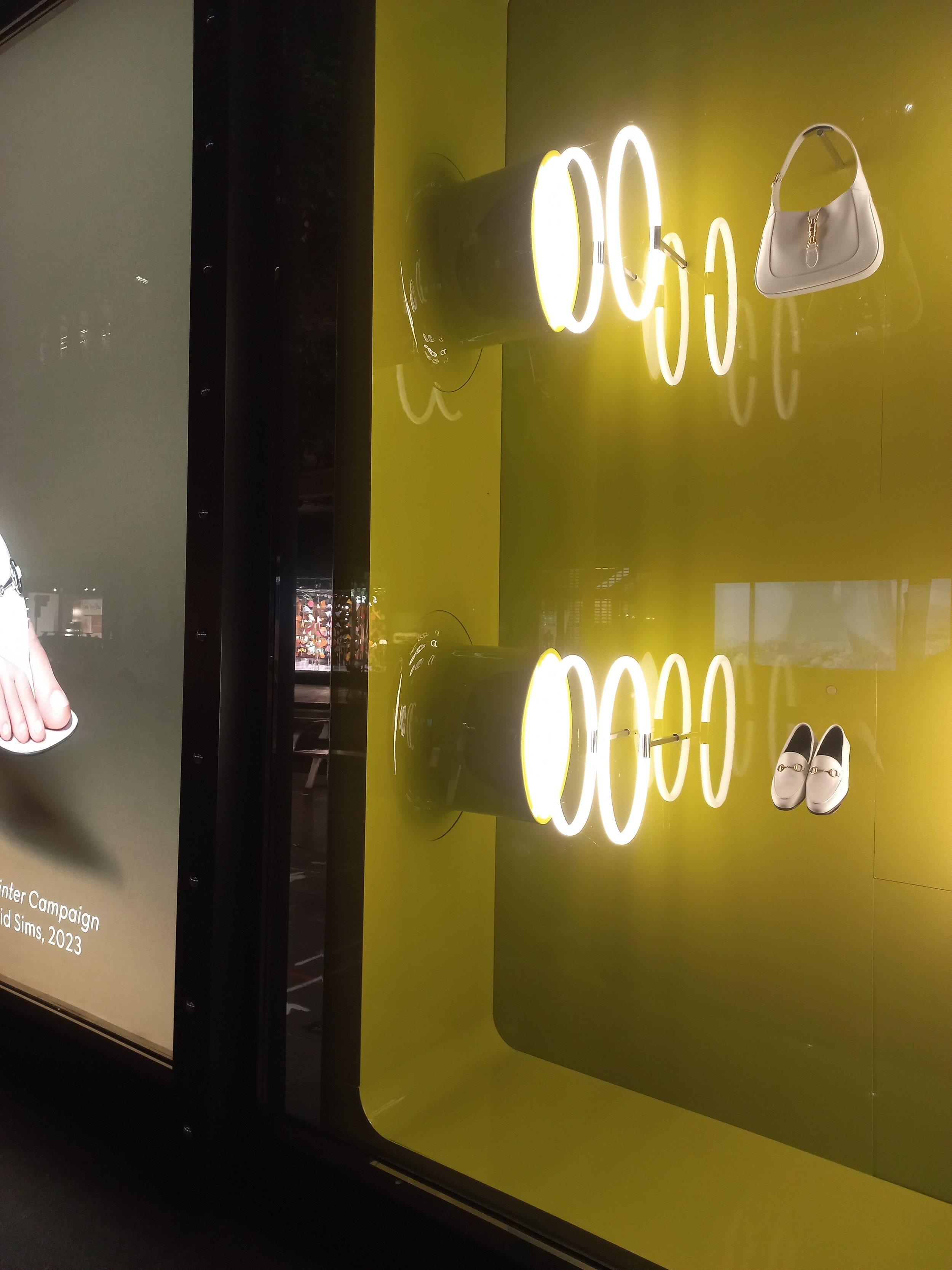 Bright yellow wall with illuminated neon Custom built props, spray booth for cylindrical structures and a large white curved structure mounted on concrete bases. Custom high end luxury retail brands window dressing, installation HR Productions Sydney