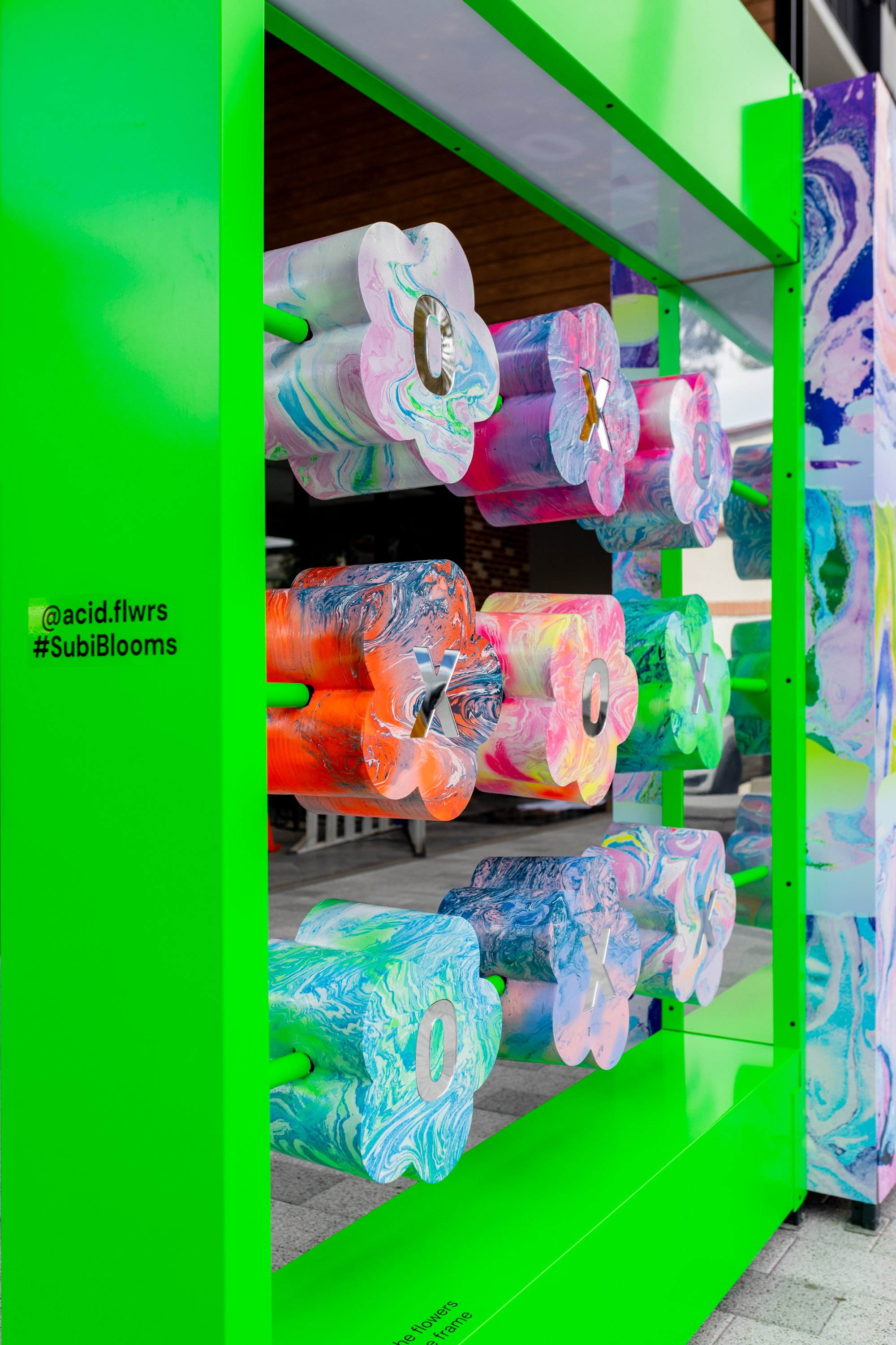 Custom built artist collaboration. ACID FLWRS Perth outdoor installaton. neon colours. Colorful dipped florals on green display stand in an outdoor setting, neon green large stand