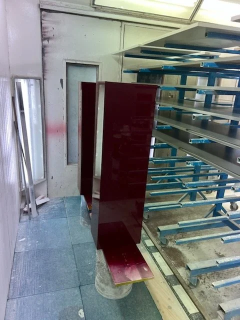 Spray booth metal shelves, a red cabinet, and a few metal racks on wheels. HR Productions custom props, plinths, high gloss burgundy red with high gloss pedestal base. High end retail installation. Sydney, custom built. 