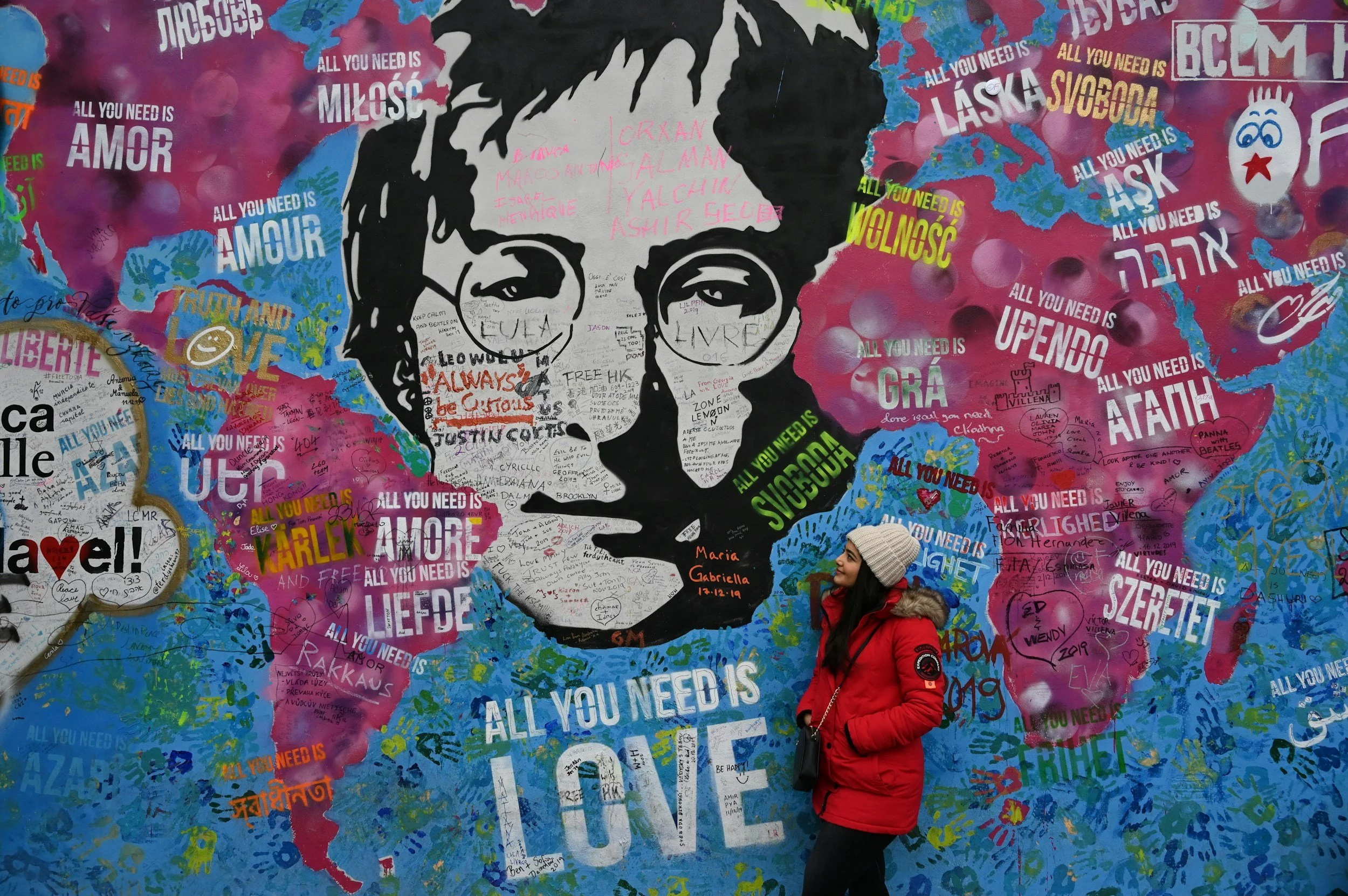 Liverpool street mural with John Lennon's face and All You Need Is Love text, visitor standing in front