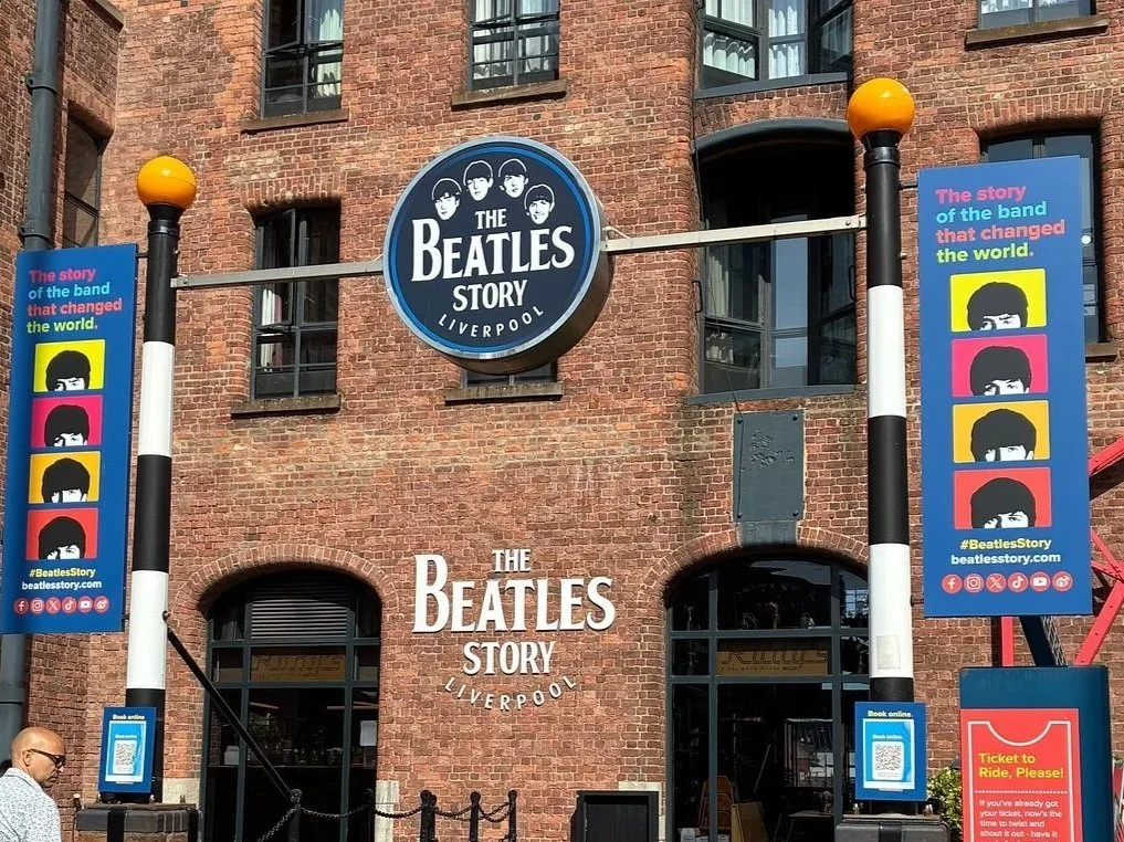 Billboards outside The Beatles Story museum in Liverpool with colourful posters and a circular Beatles logo sign