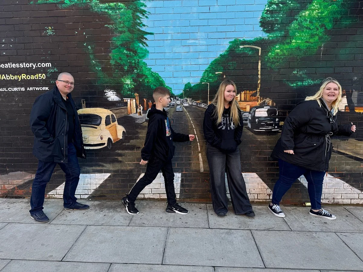 Four people standing in front of painted Liverpool street scene mural