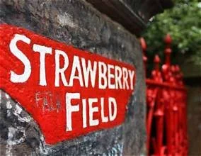 Strawberry Field red sign on stone wall with red gate and greenery