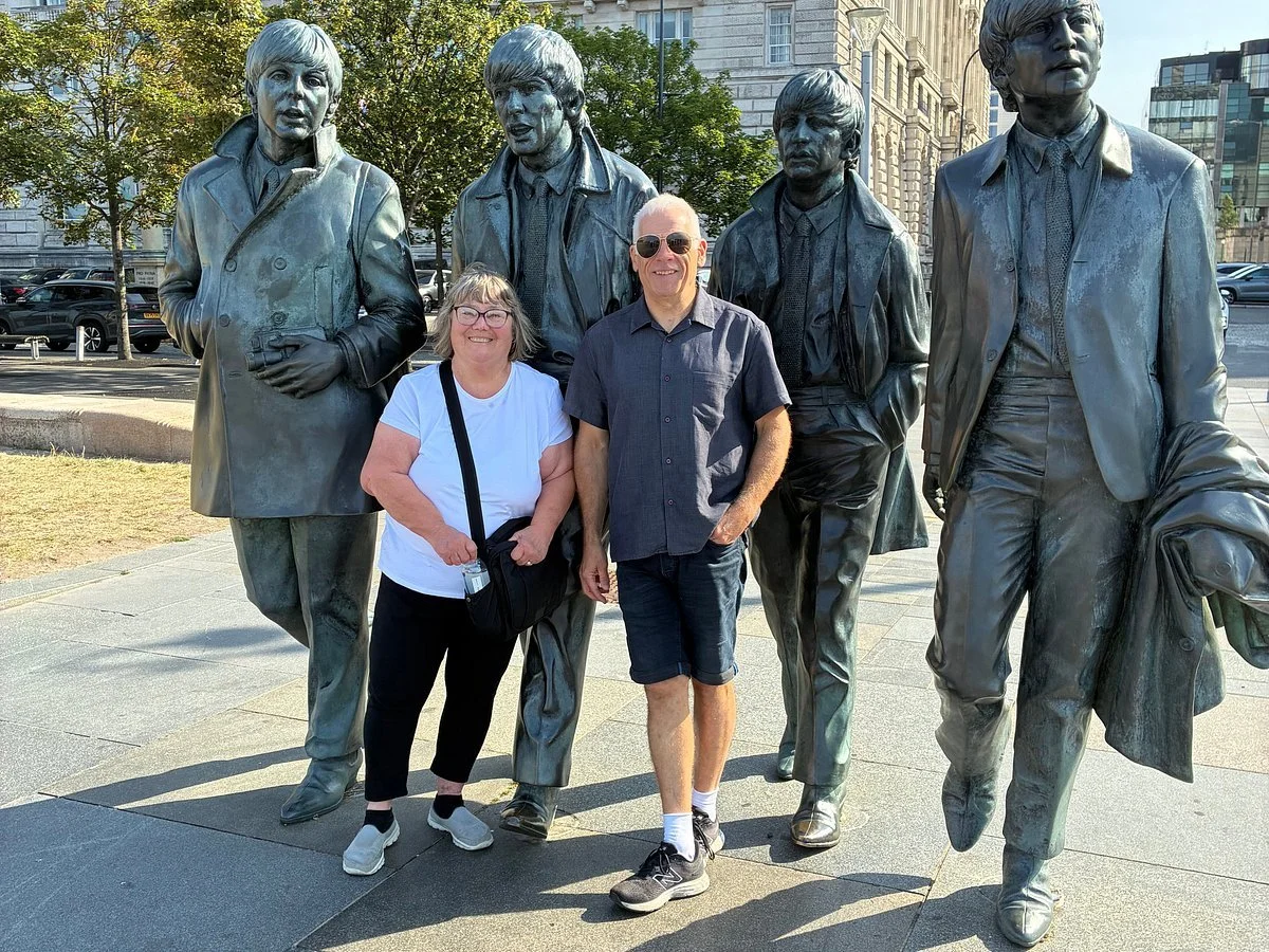 Two visitors standing in front of Beatles statues in Liverpool city centre