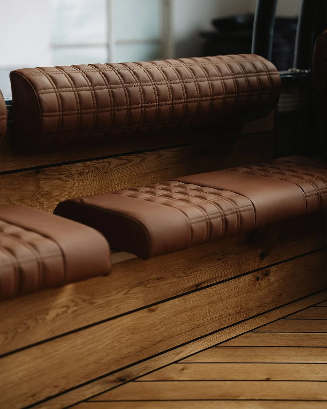 Close-up of leather cushioned booth seating with a wooden table and wood-paneled floor in a Land Rover Defender.