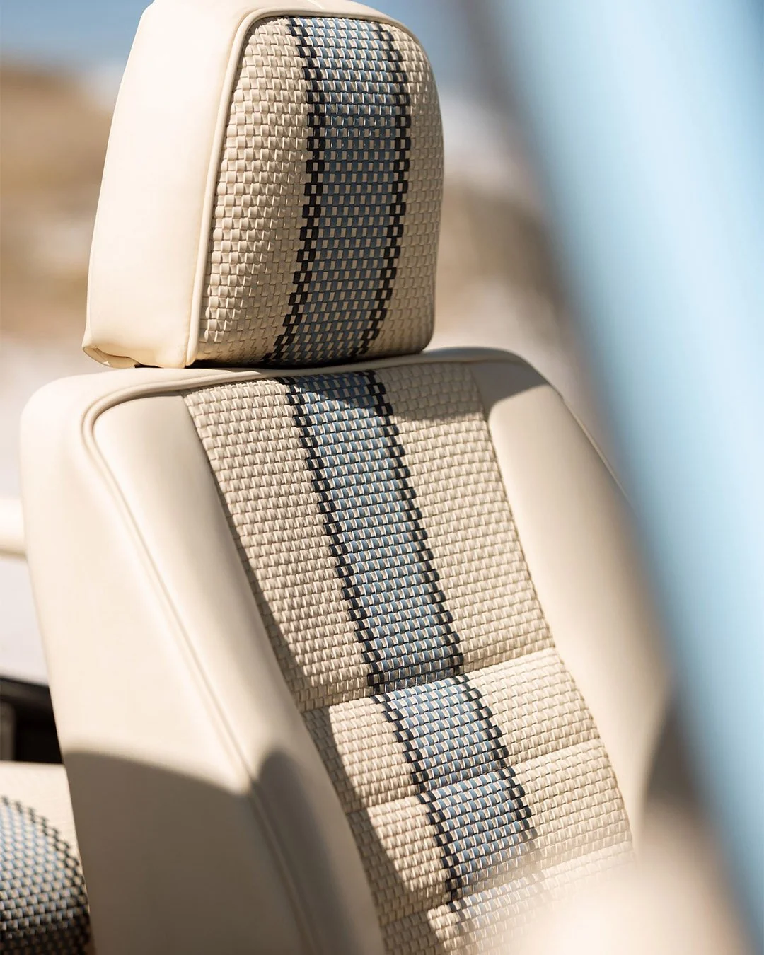 Close-up of vintage car seats with beige and black checkered fabric upholstery.