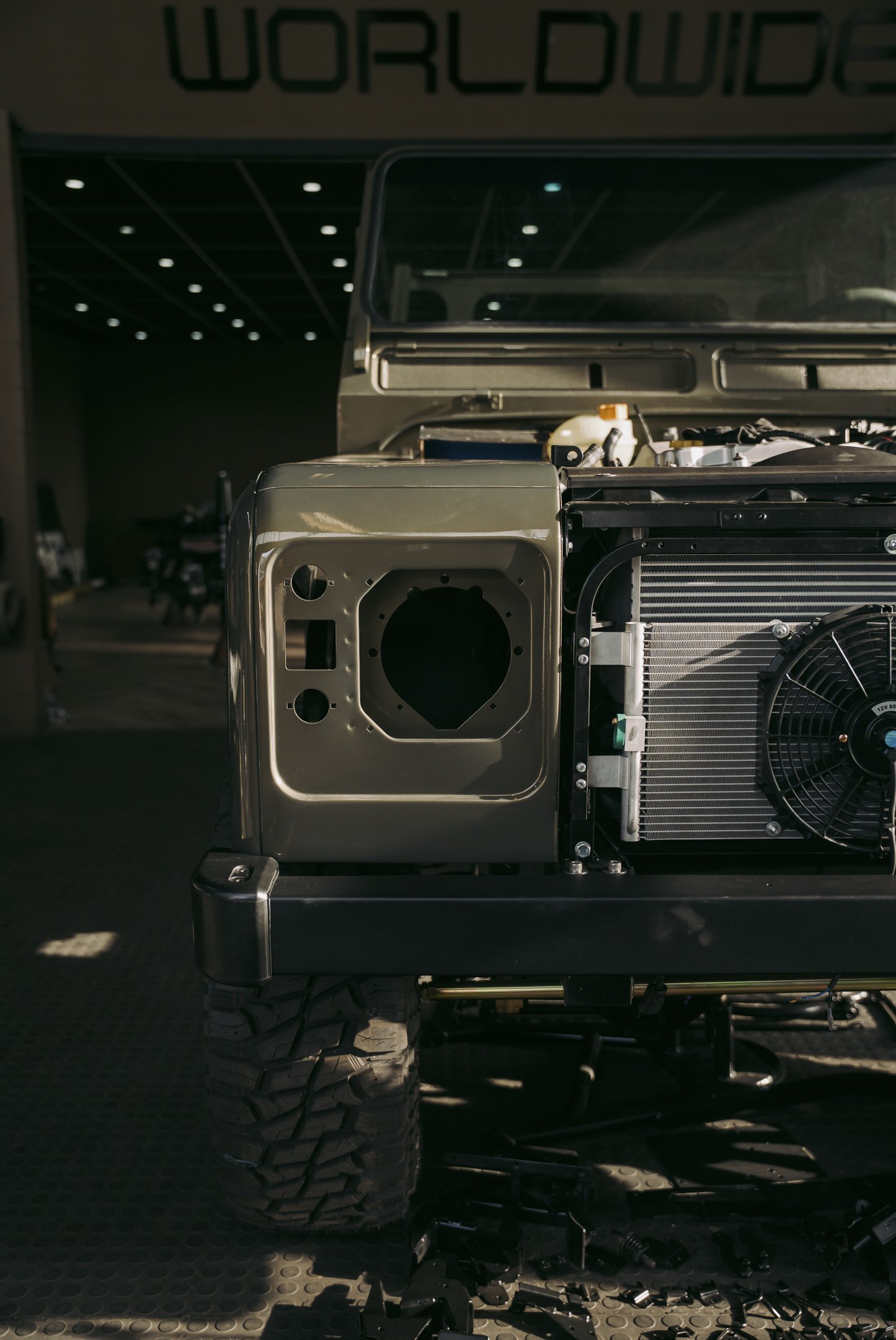 Close-up of a partially disassembled vehicle engine with visible parts and radiator, set against a dark background with the word 'WORLDWIDE' displayed at the top.