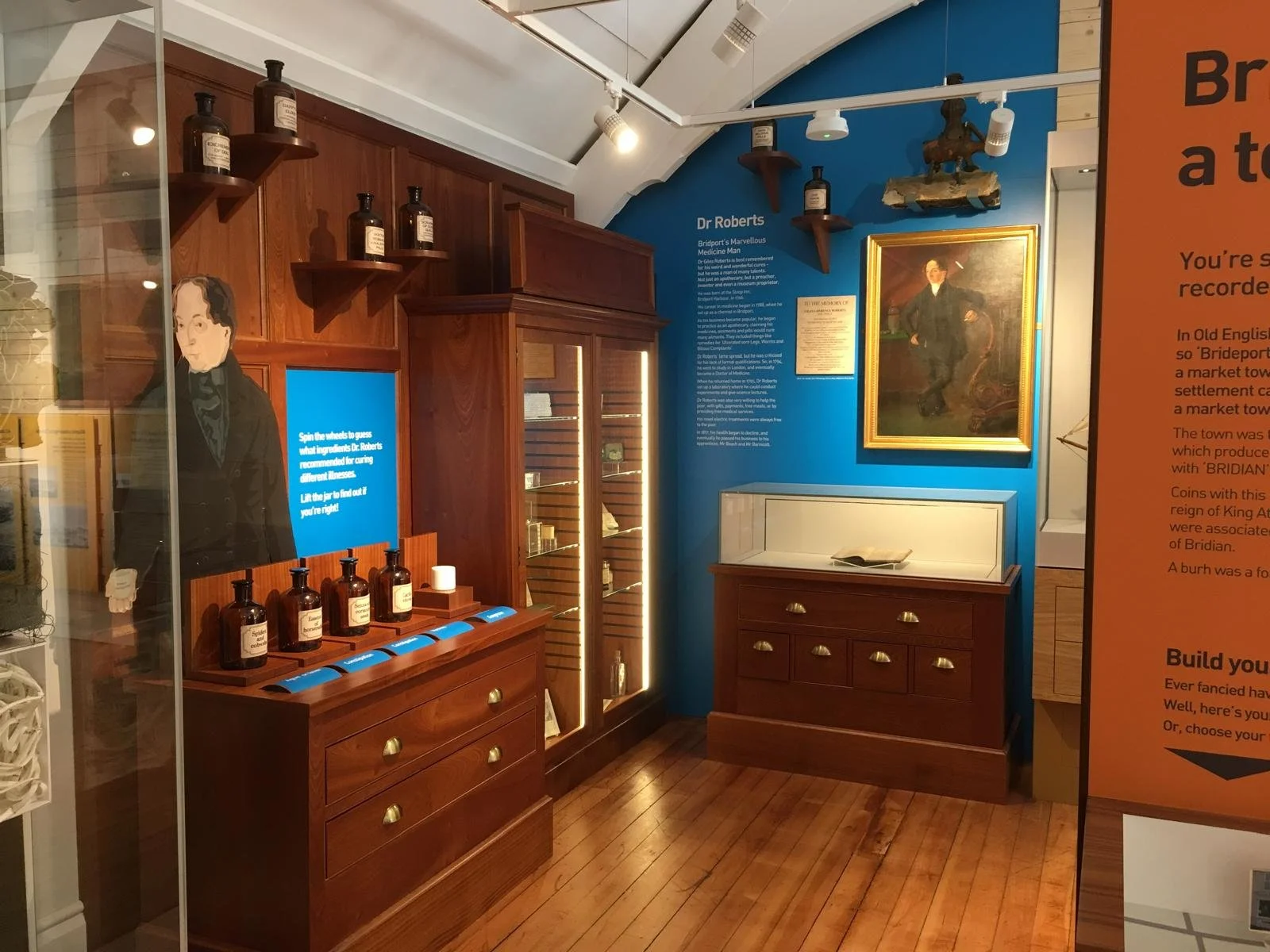 A museum exhibit dedicated to Dr. Roberts with vintage medicine bottles, a portrait of a man in a suit, and informational plaques on a blue wall.