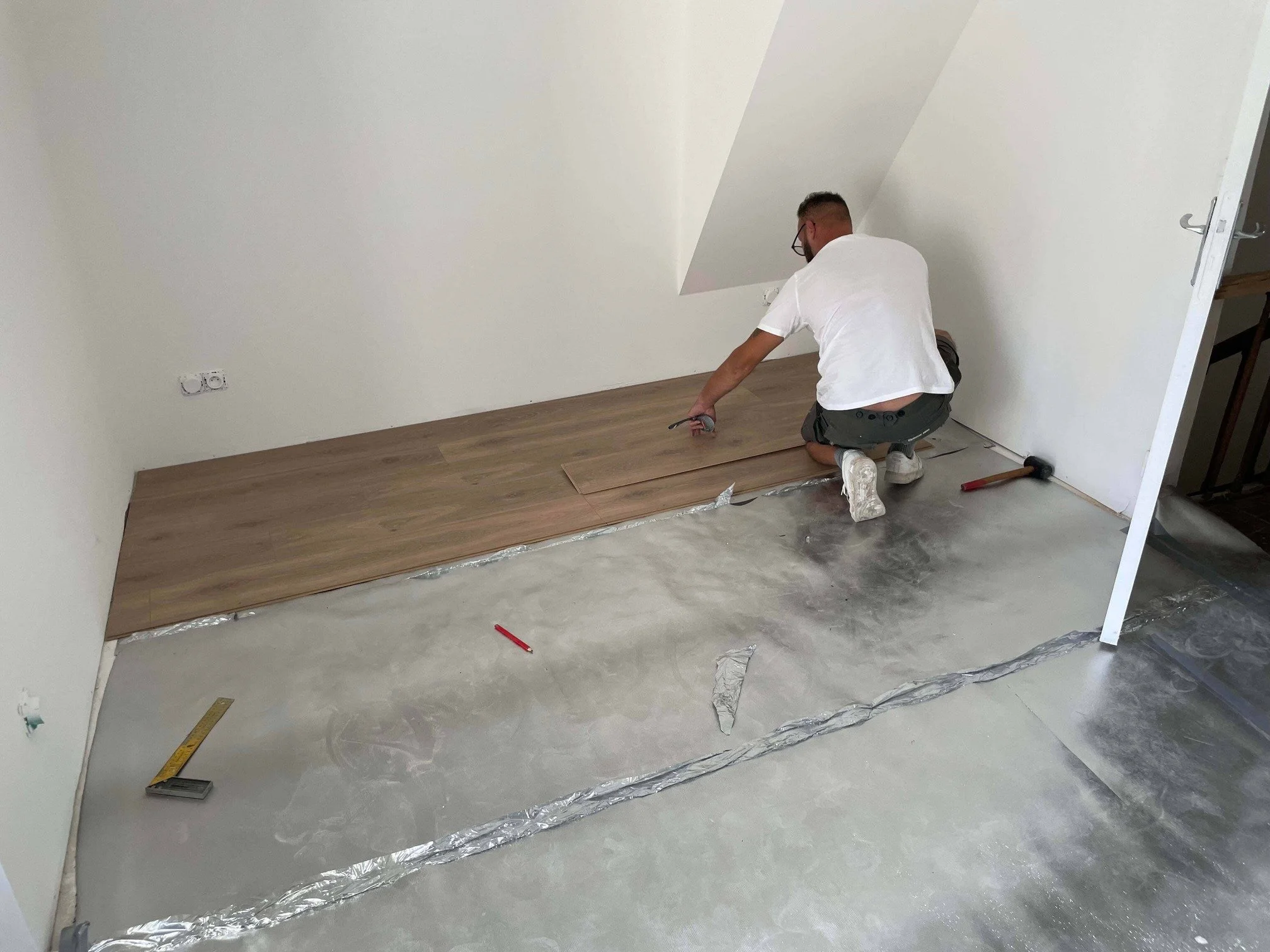 Pose de parquet flottant en bois clair par Mario Delorme (partenaire de DLM Services) à Mayenne, en Mayenne.