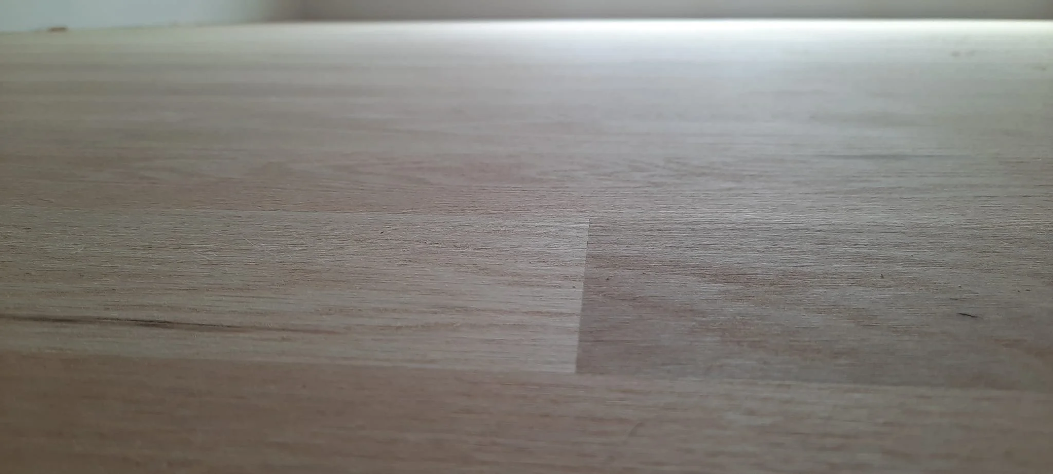Close-up of a wooden surface with a light wood grain pattern.