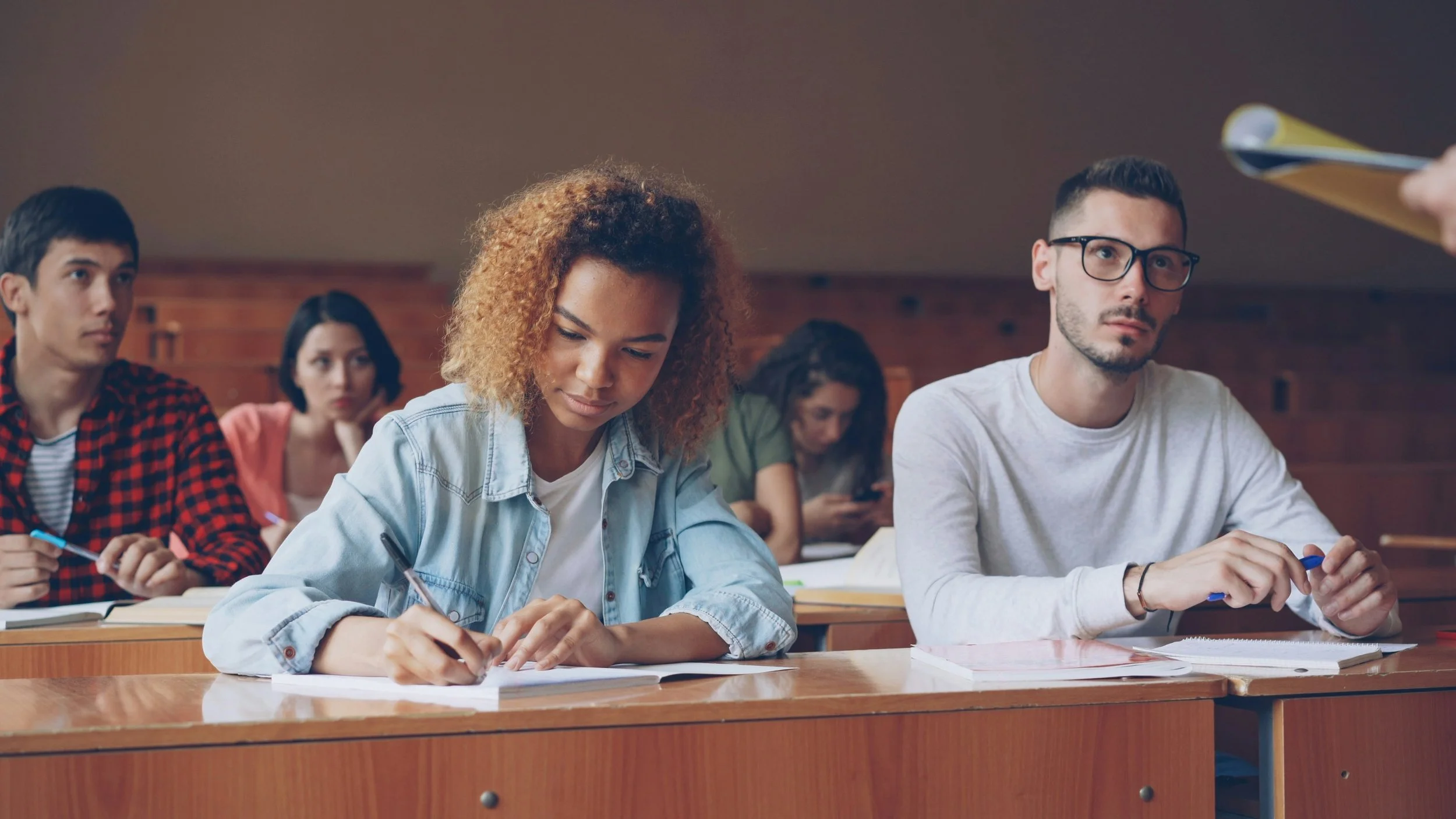 Students in a classroom taking notes and listening to instruction.
