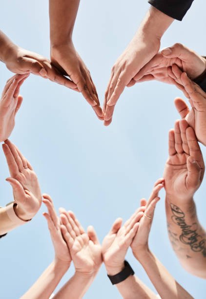 Multiple hands forming a heart shape against a light blue background.