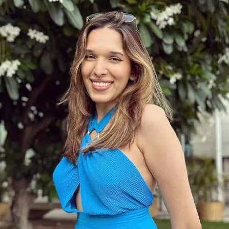 Dr. Trinetra Haldar Gummaraju, Karnataka's first openly transgender doctor and Indian actress, smiling outdoors in a bright blue dress.