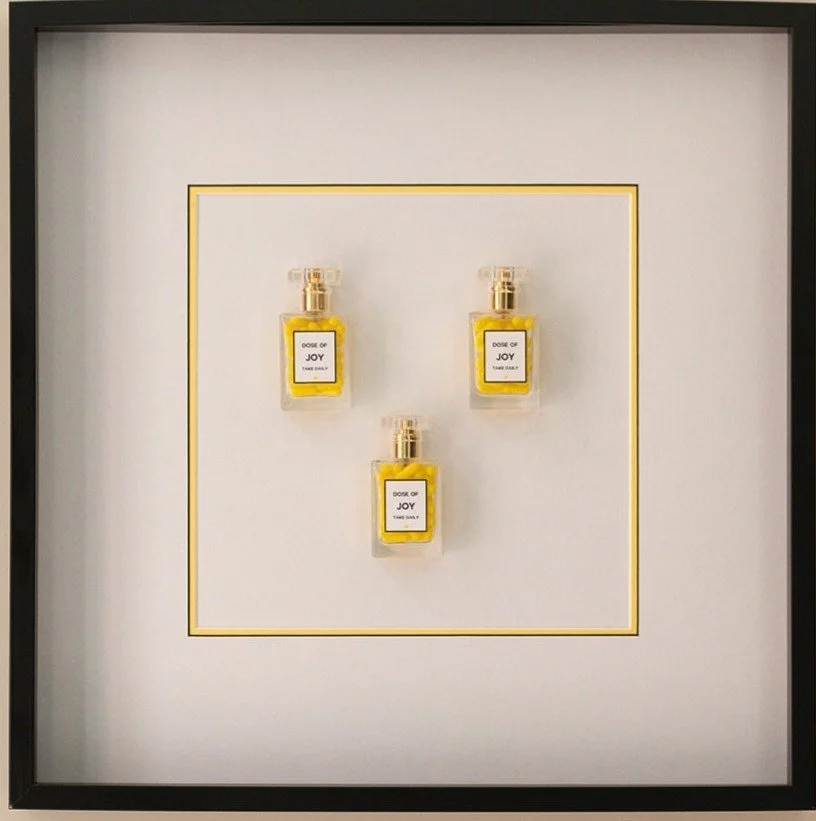 Three small perfume bottles labeled 'Dose of Joy' arranged on a white background with a gold border.