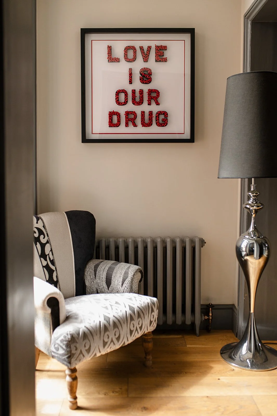 Love is Our Drug by Julie Langford, contemporary pill art created with red pharmaceutical capsules and 
displayed in a framed interior setting.