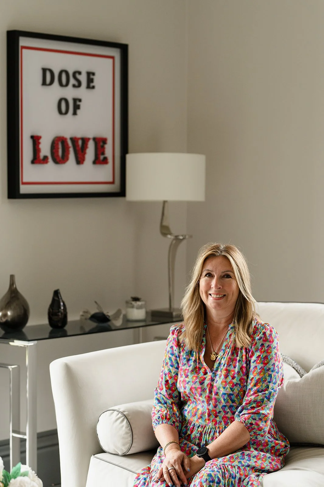 Julie Langford seated beside her "Dose of Love" artwork, part of her contemporary mixed-media art collection.