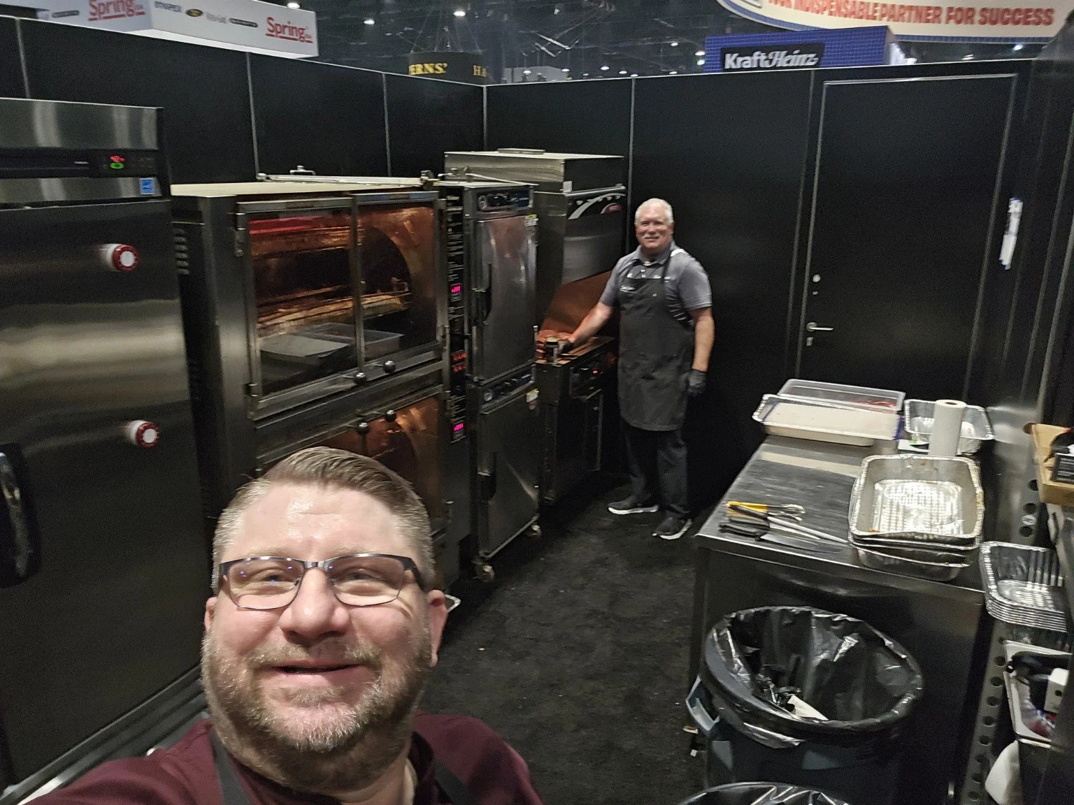Brian Brozovic with a colleague in a commercial food processing kitchen at a trade show.