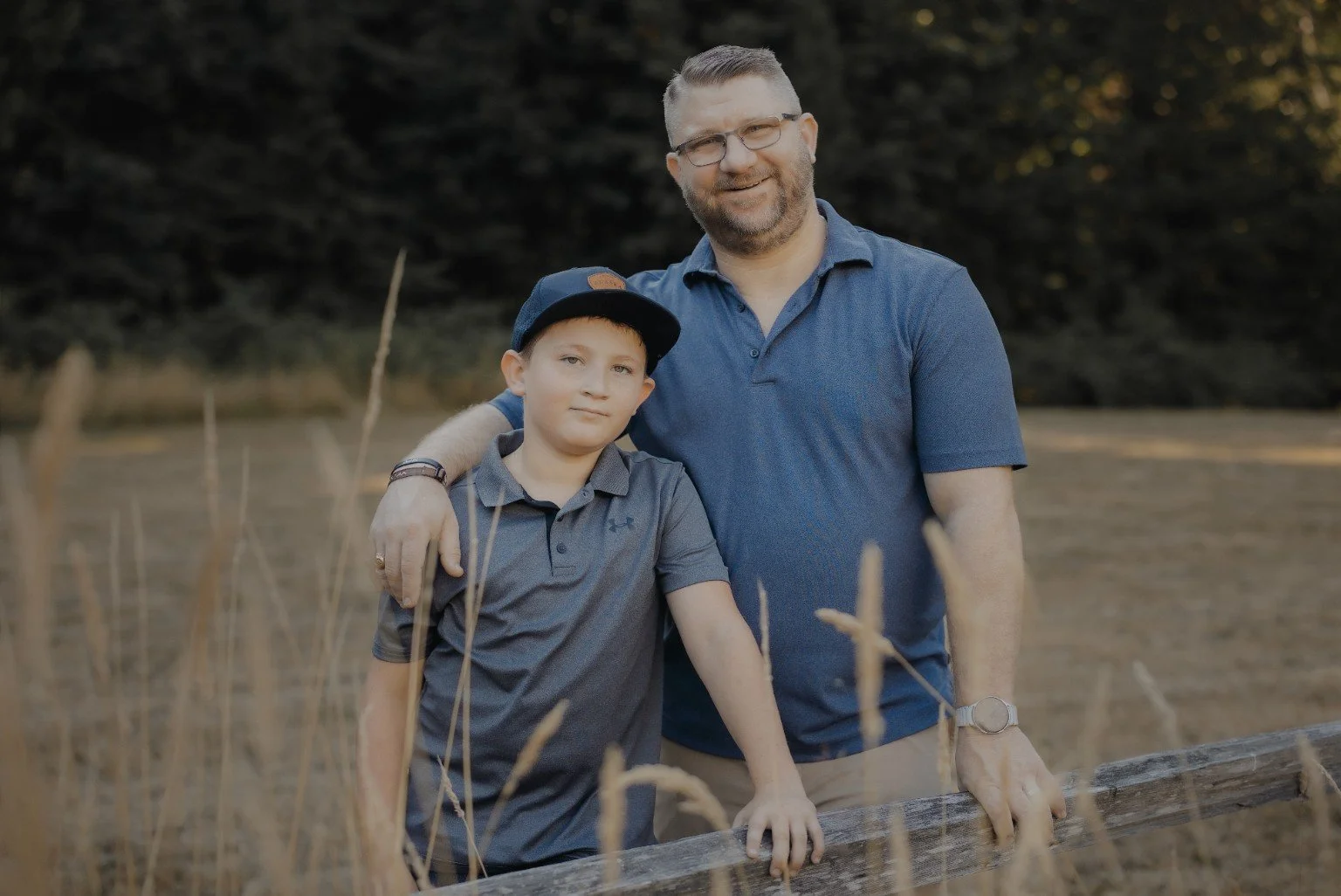 Brian Brozovic and his son together at a wooden fence in a rural setting.