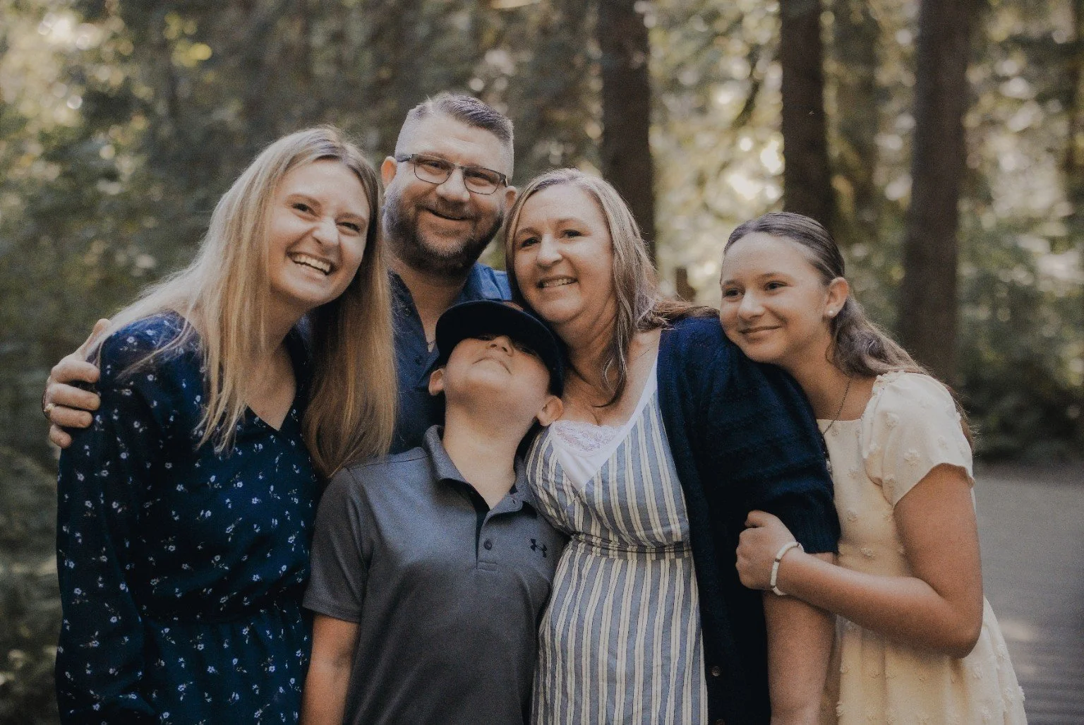 Brian Brozovic with his wife and family outdoors in a wooded setting.
