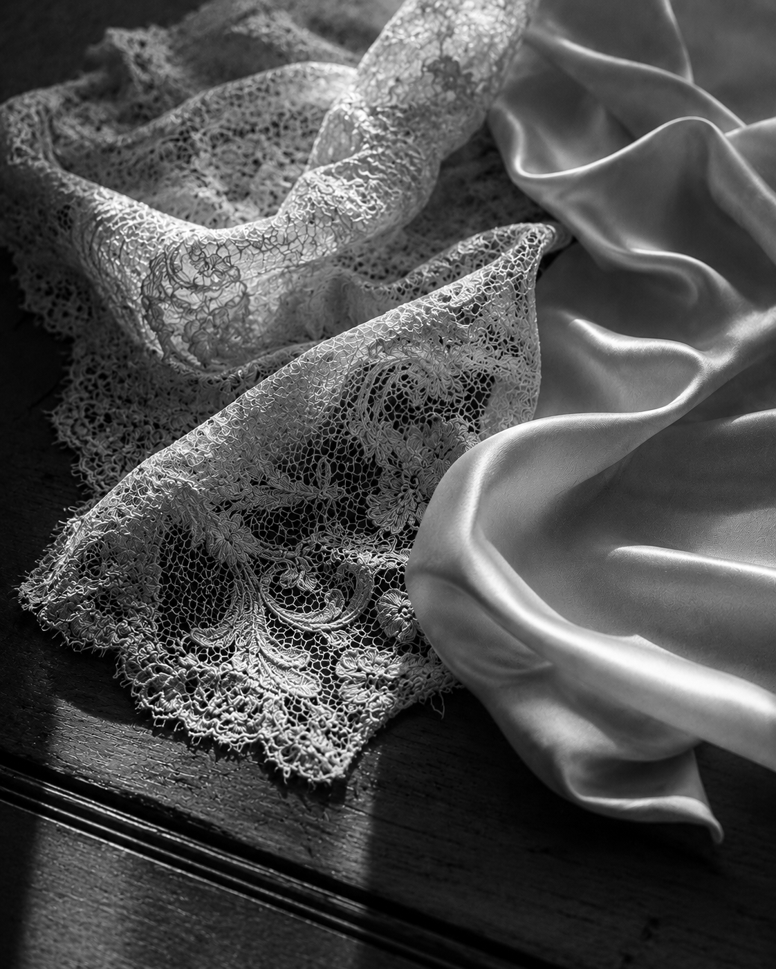 Black-and-white close-up photograph of lace and satin fabric draped together