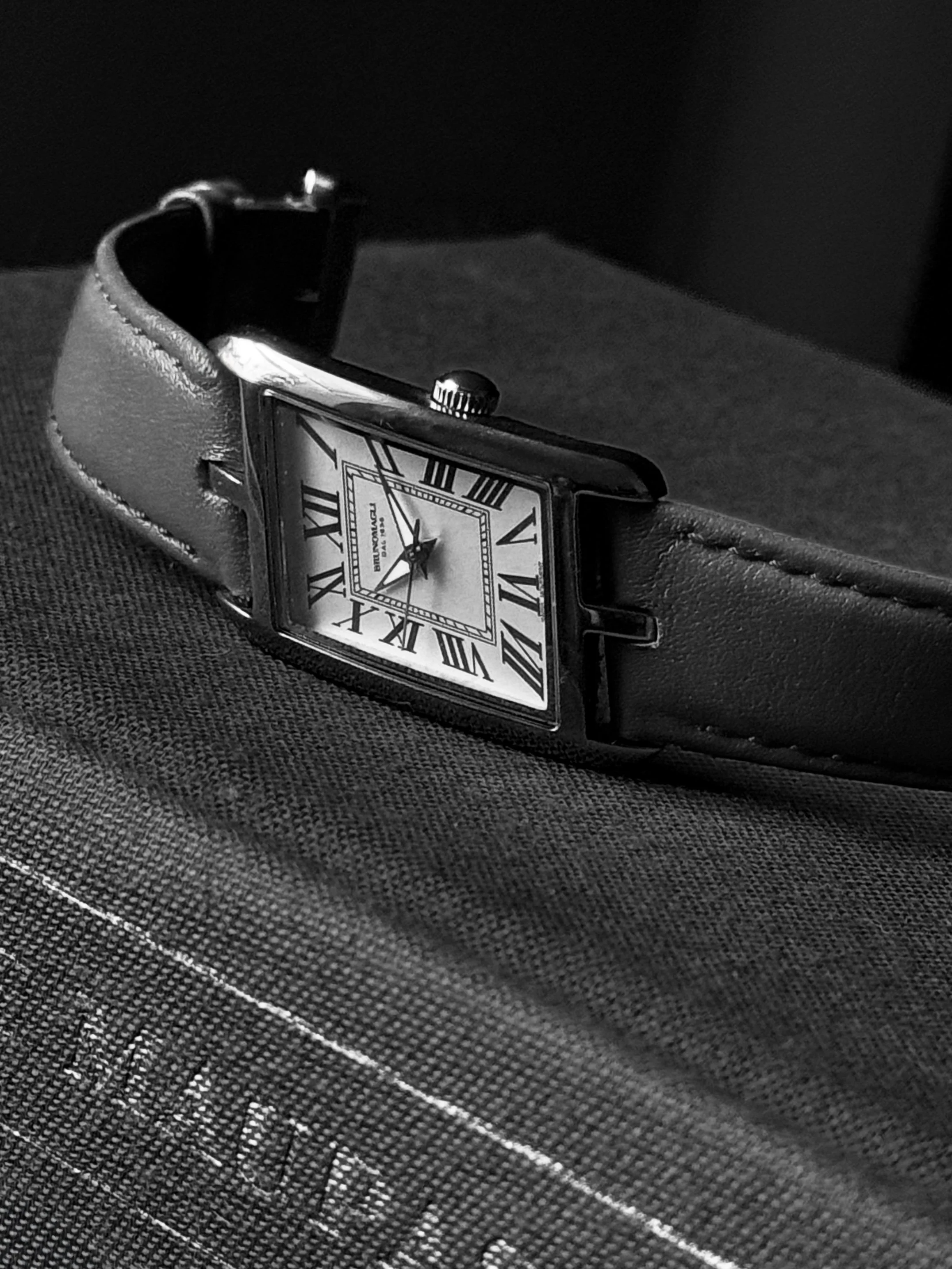 Black-and-white photograph of a sculptural metal cuff bracelet and a pair of stud earrings illuminated by a beam of light