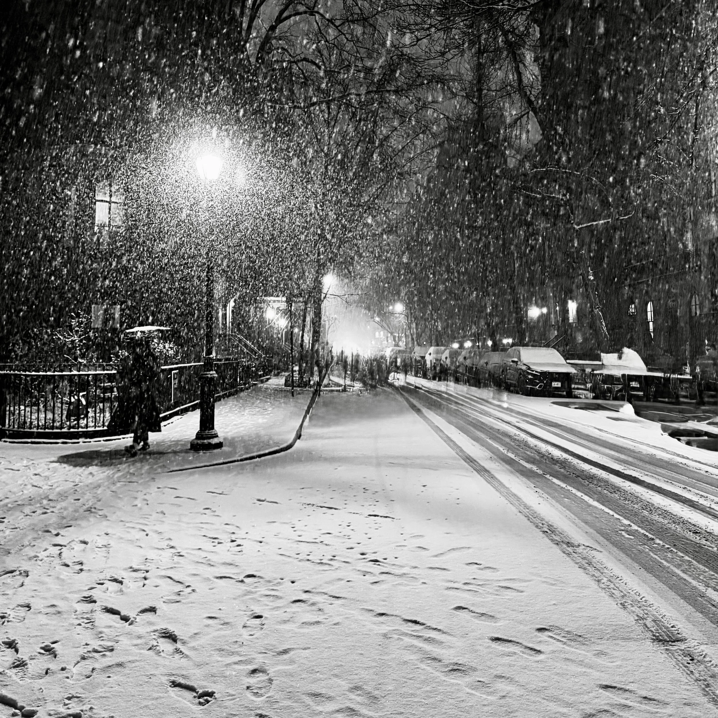 Black-and-white photograph of snow falling at night on a residential street in Manhattan's East Village