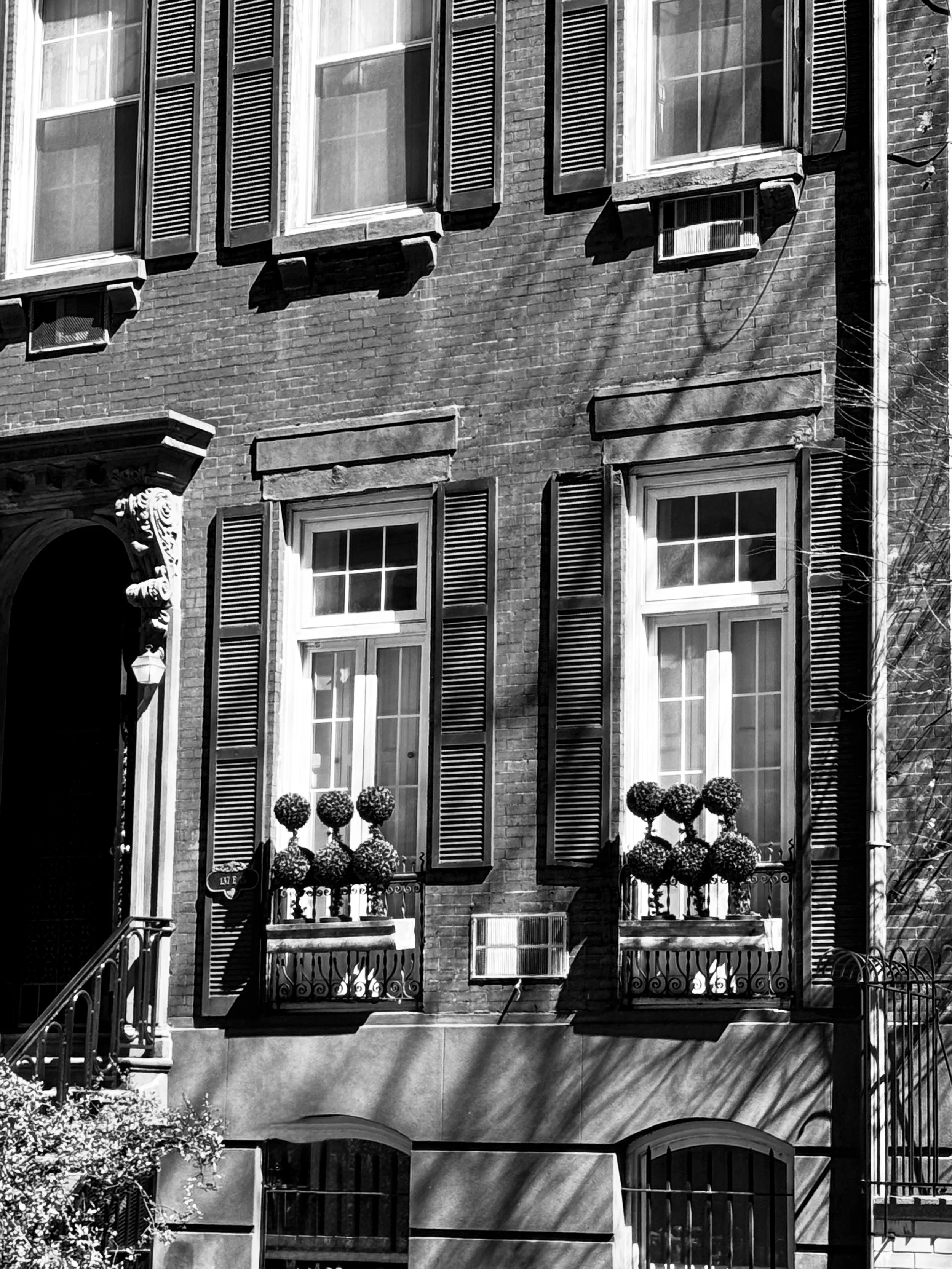 Black-and-white photograph of a brick townhouse façade with shuttered windows and flower boxes in Gramercy Park, Manhattan