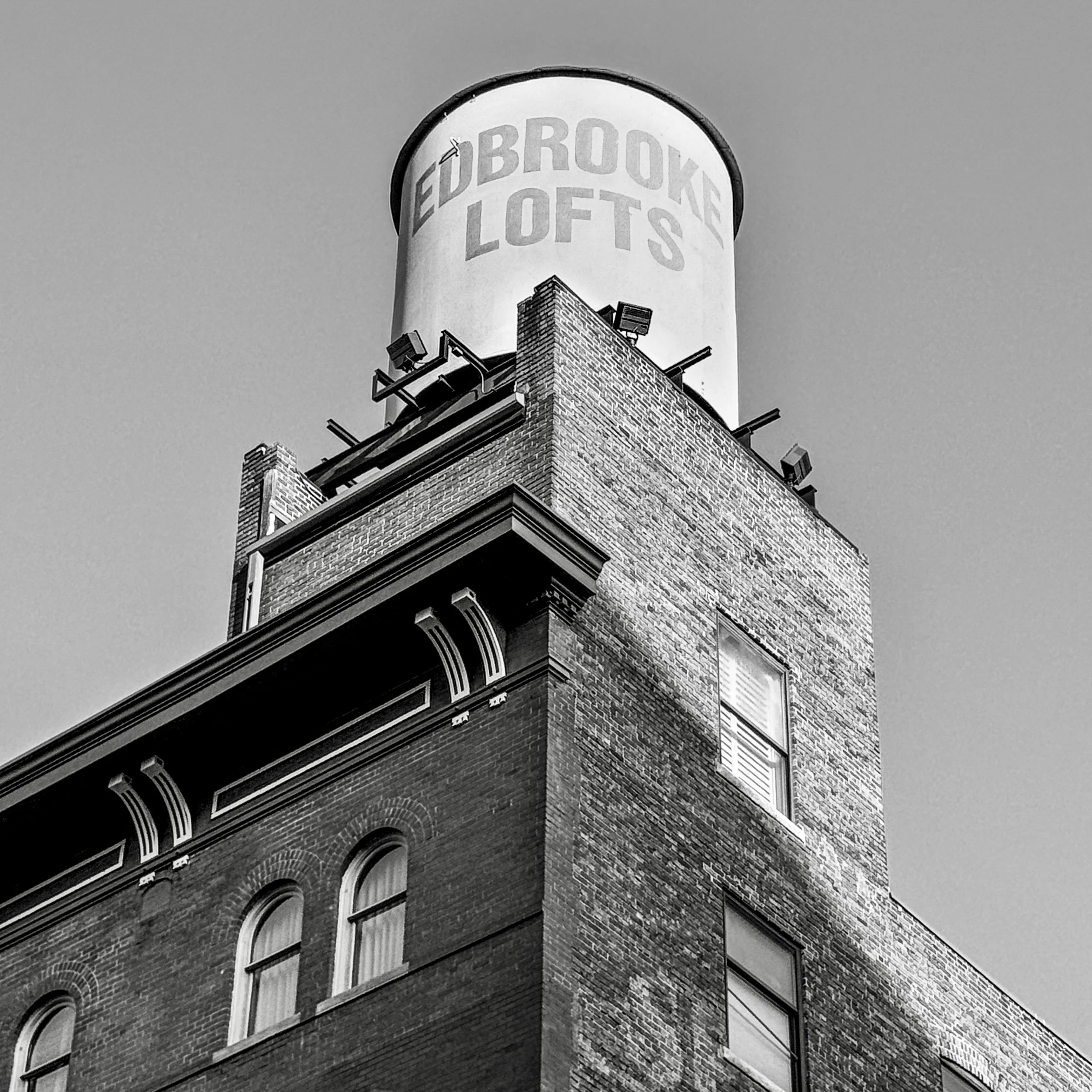 Black-and-white photograph looking up at a brick industrial building and rooftop water tank in Denver, Colorado