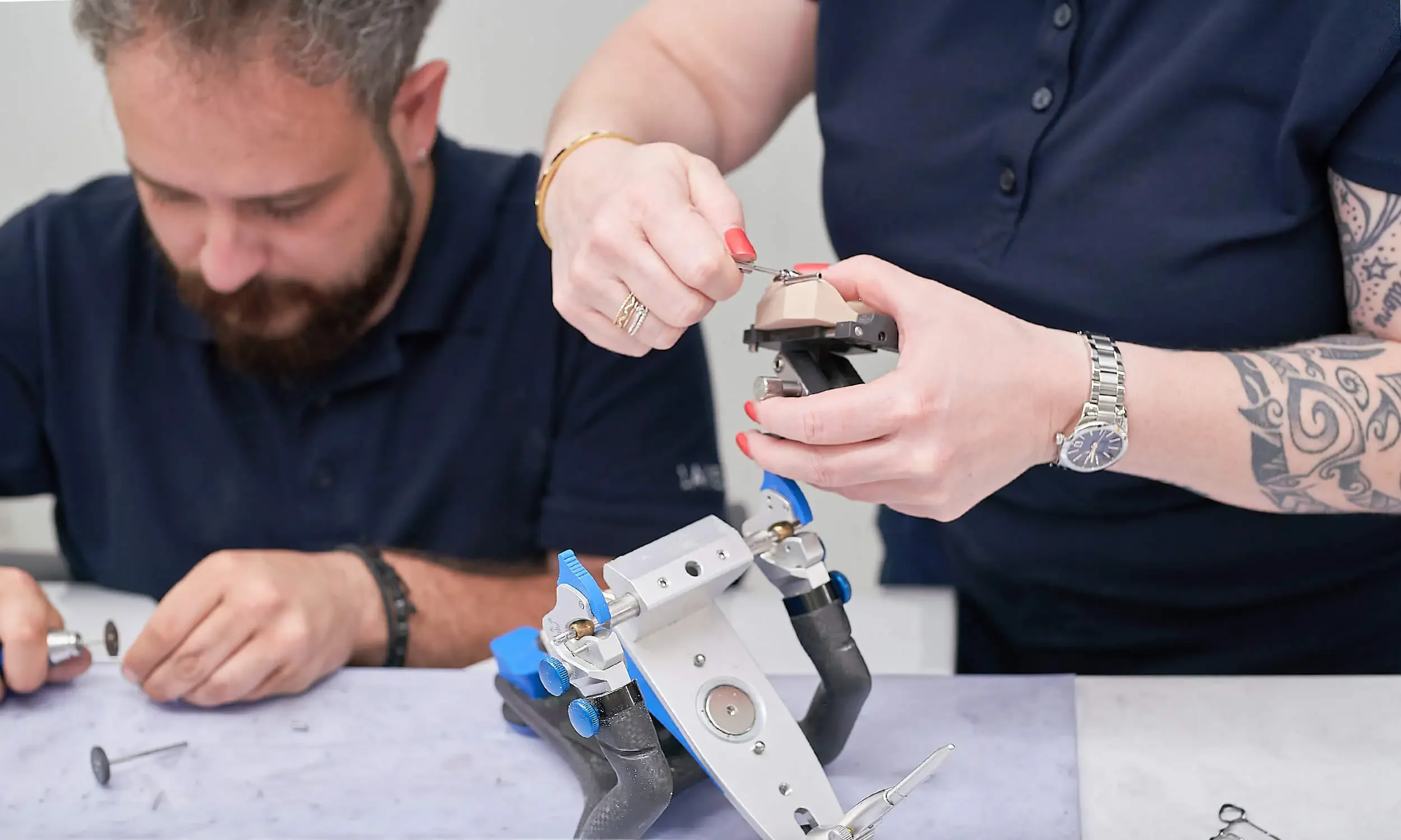 Zwei Menschen arbeiten gemeinsam an einem technischen Gerät, möglicherweise einem Mikroskop, in einem Labor oder Werkstatt, während sie Details an dem Gerät anschauen und anpassen.